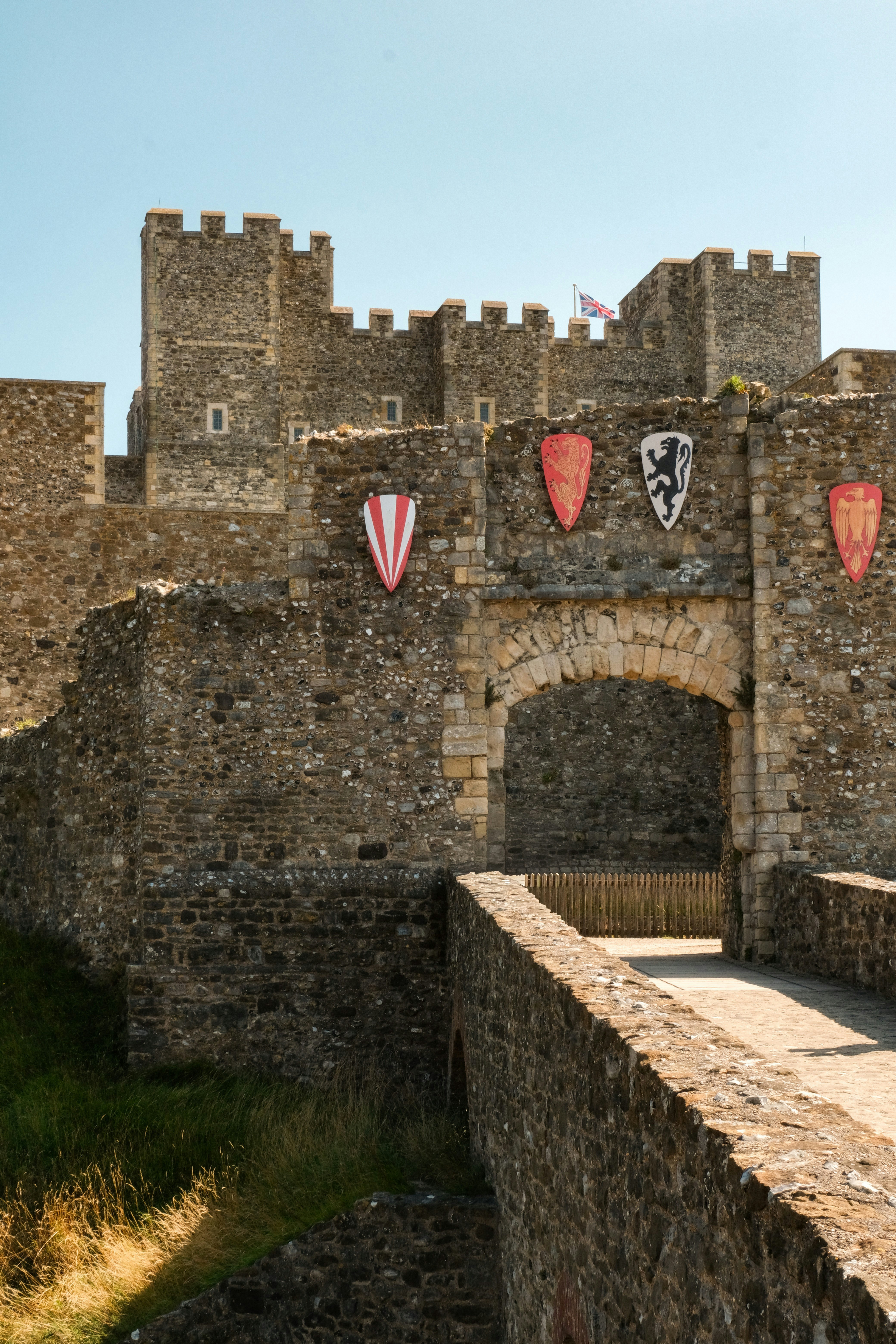Stone castle gatehouse with flags and shields