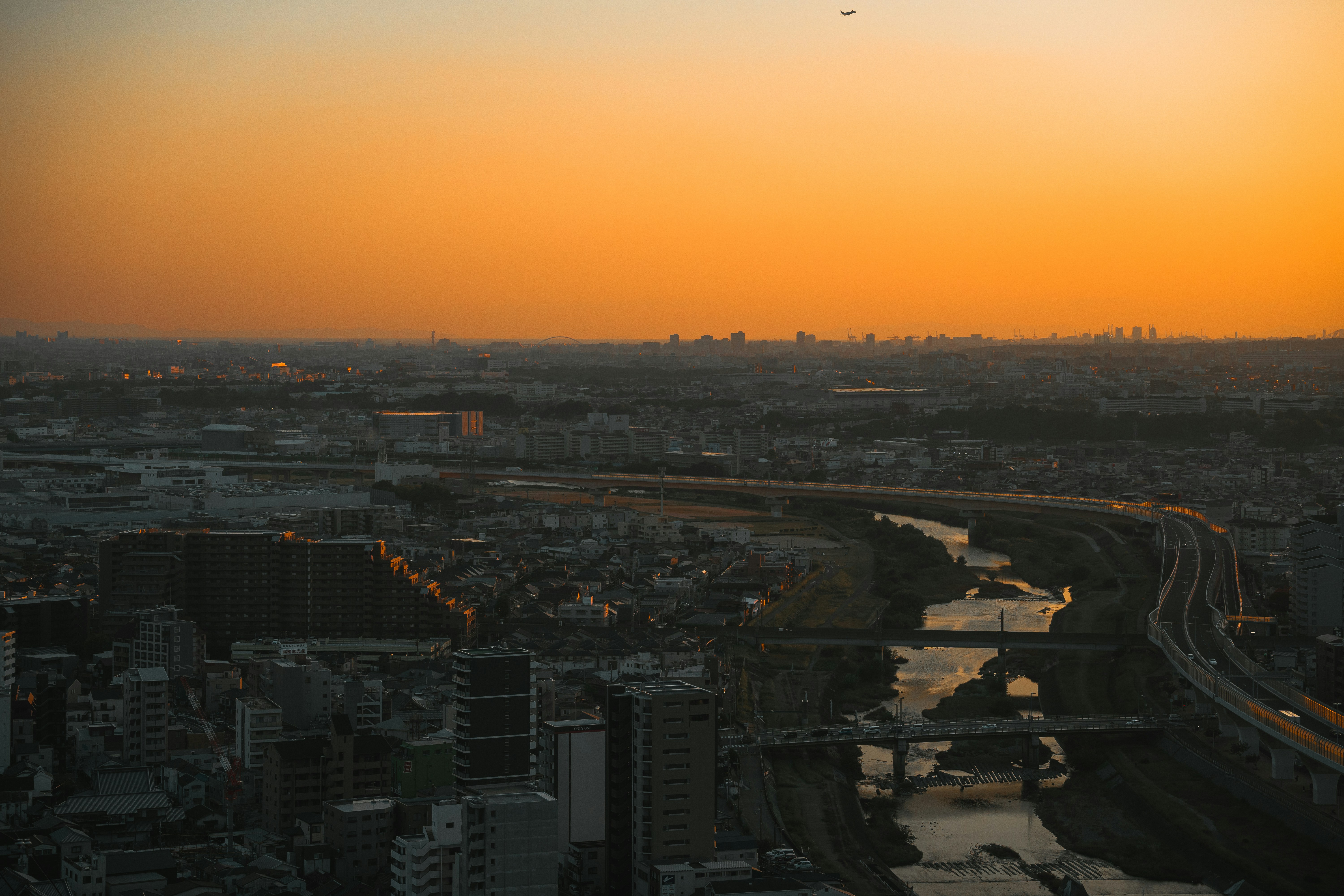 Cityscape at sunset with a river and highway.