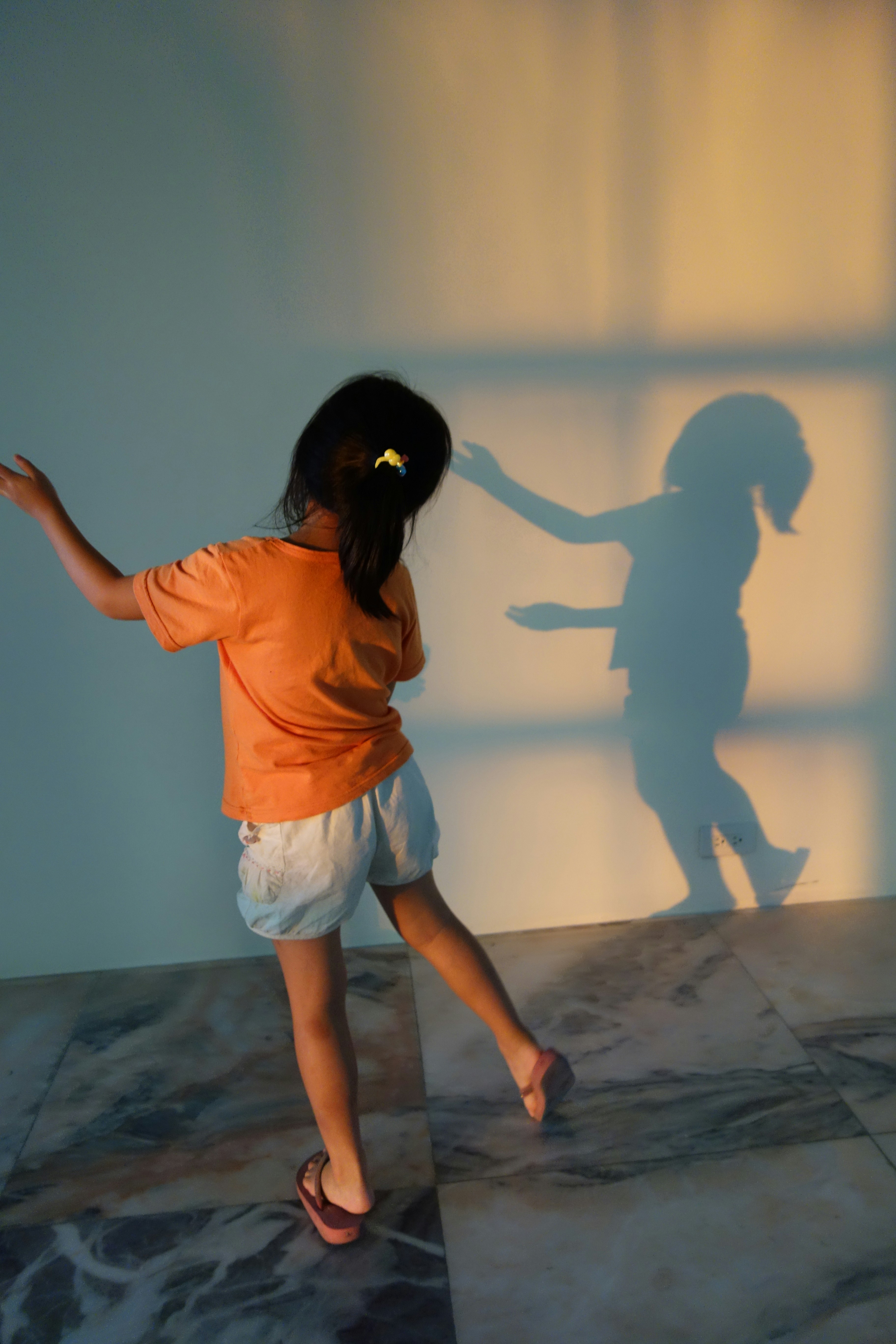 Young girl plays with her shadow on wall