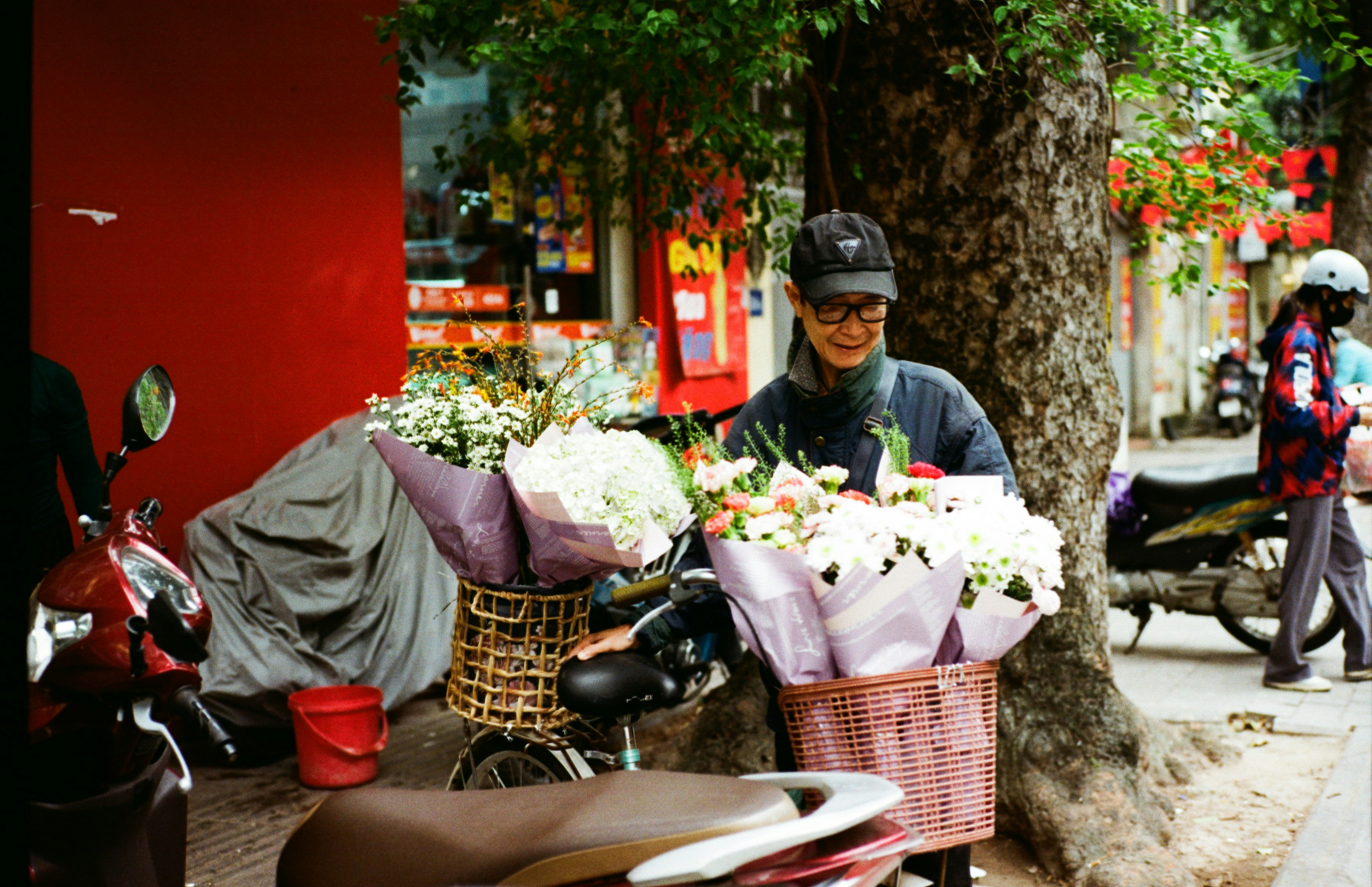 Watercolor painting of a bustling local market stall near a cherry blossom viewing area, with elderly Japanese women selling fresh local produce and traditional crafts. The atmosphere is warm and inviting.