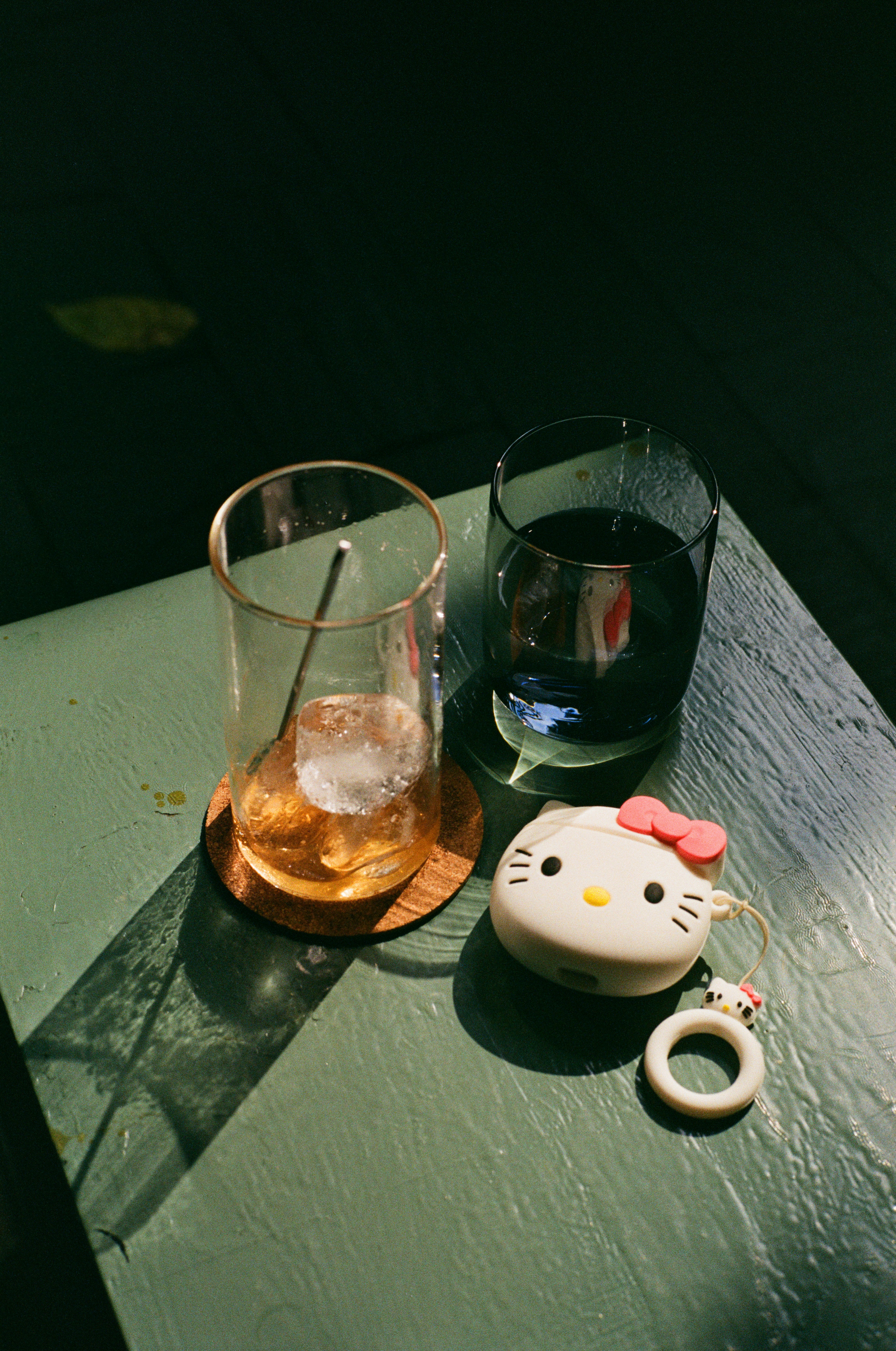 Two drinks and a hello kitty charm on a table