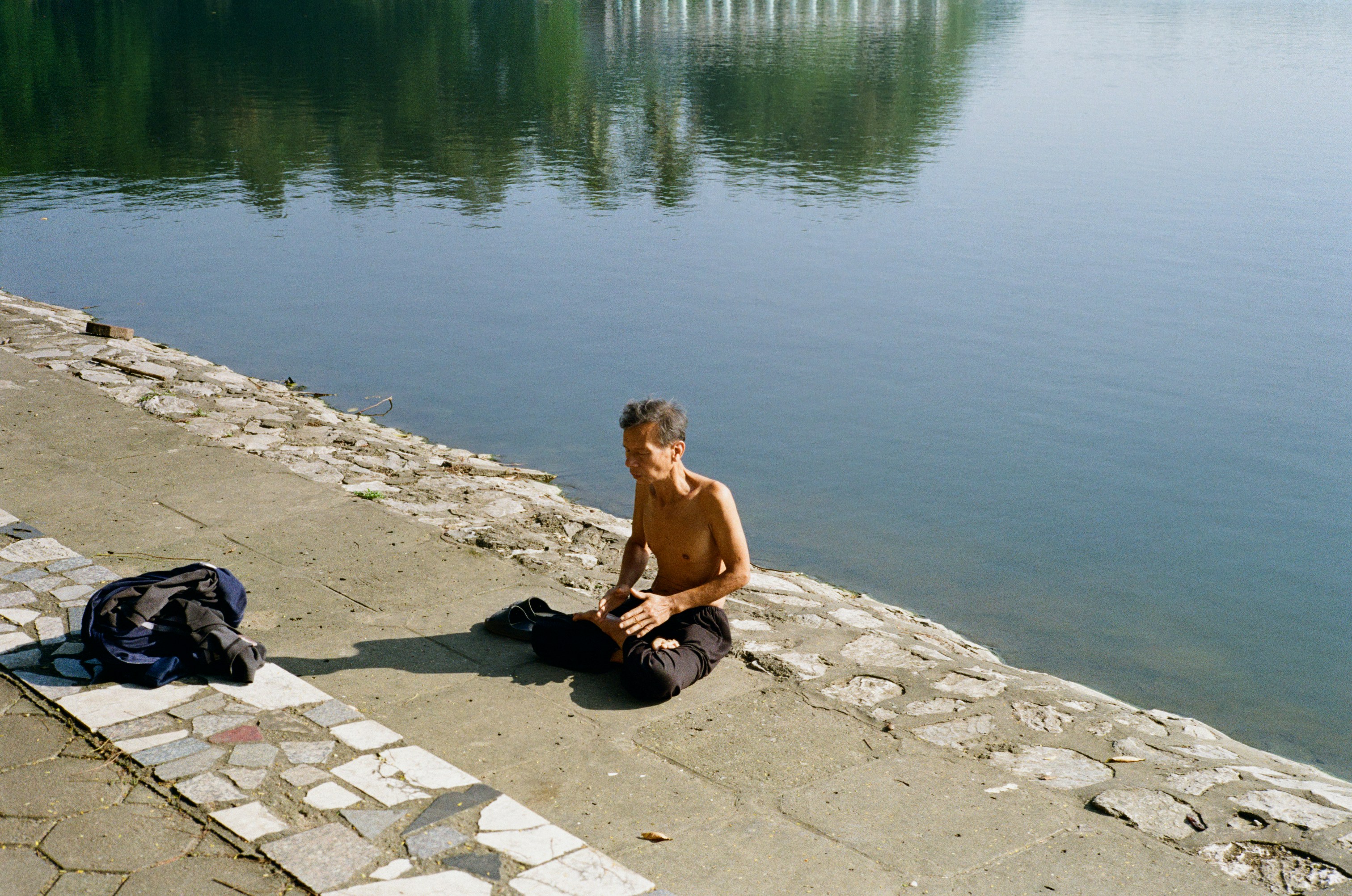 Man sitting by the water with a bag