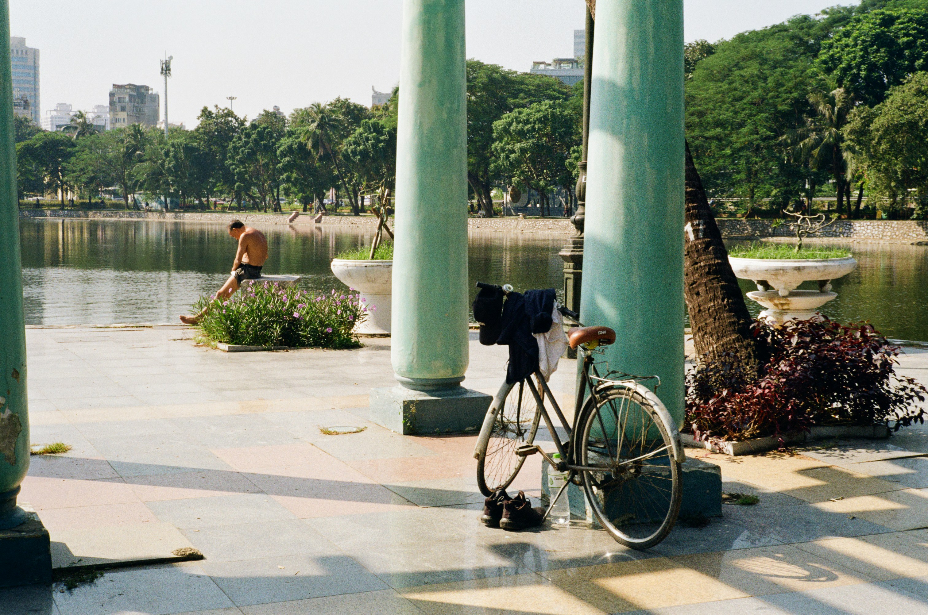 A bicycle parked near a lake with a man exercising.