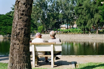 Two men sitting on a park bench by the water.