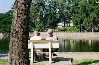 Two men sitting on a park bench by the water.