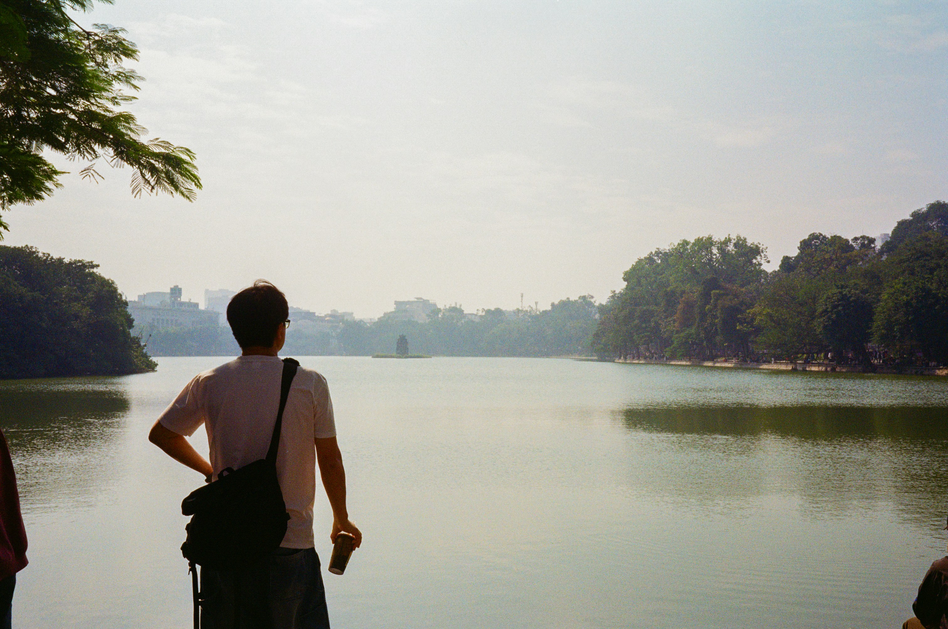 Man looking at a serene lake with trees