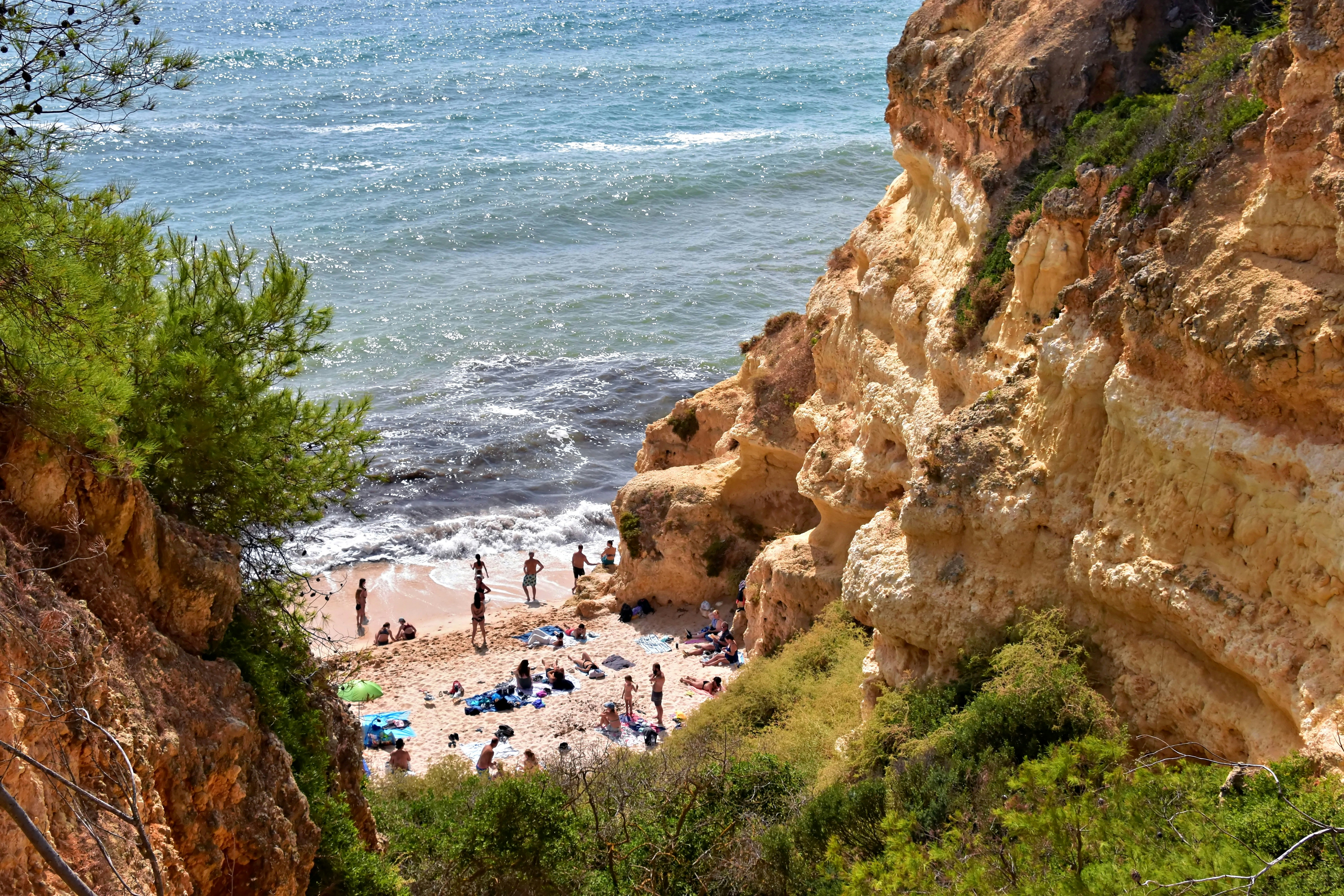 Des gens se détendant sur une plage ensoleillée entre des falaises rocheuses.