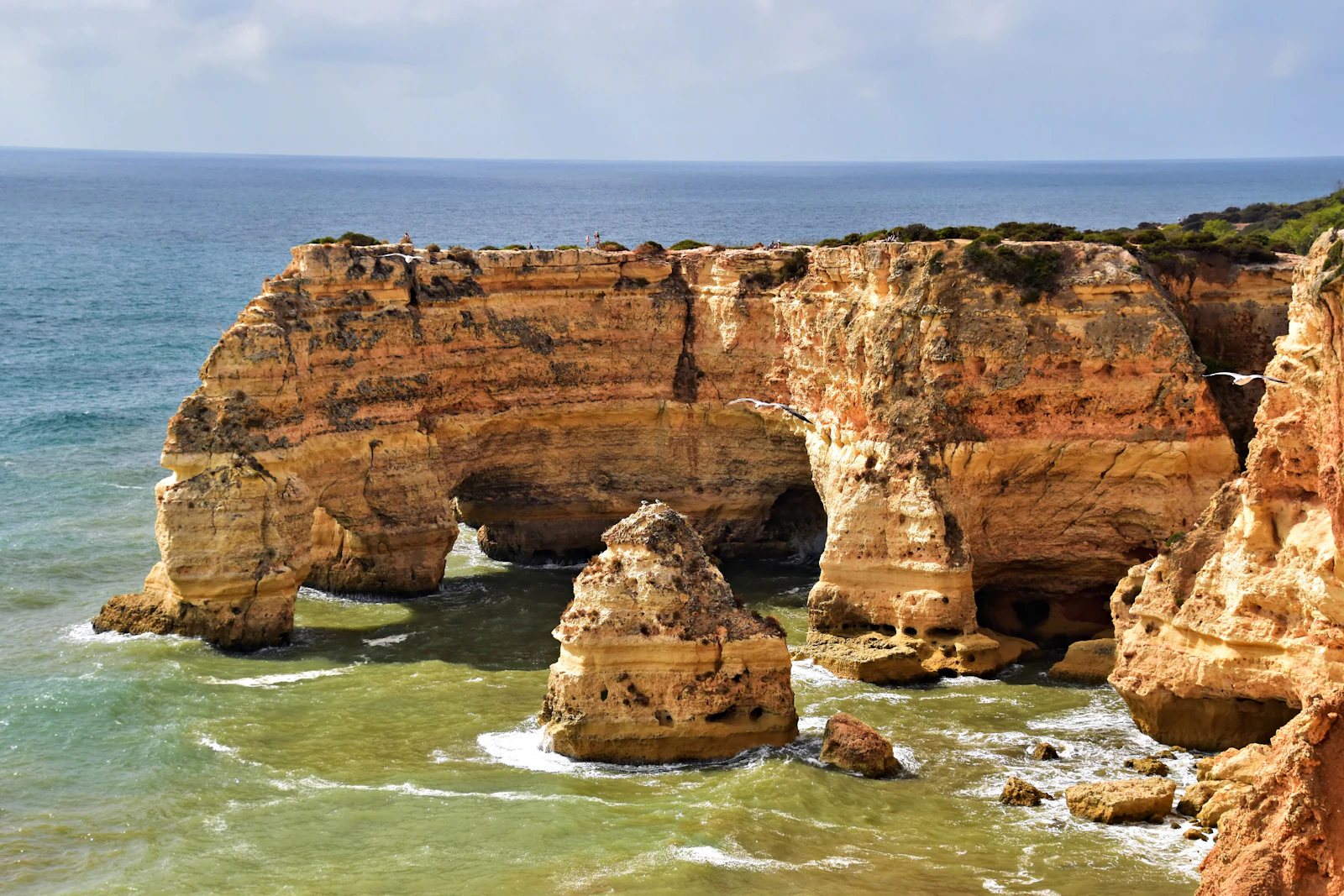 Golden sea arches and rock stacks in turquoise water on the Algarve coast, reachable by car with an Algarve eSIM for navigation