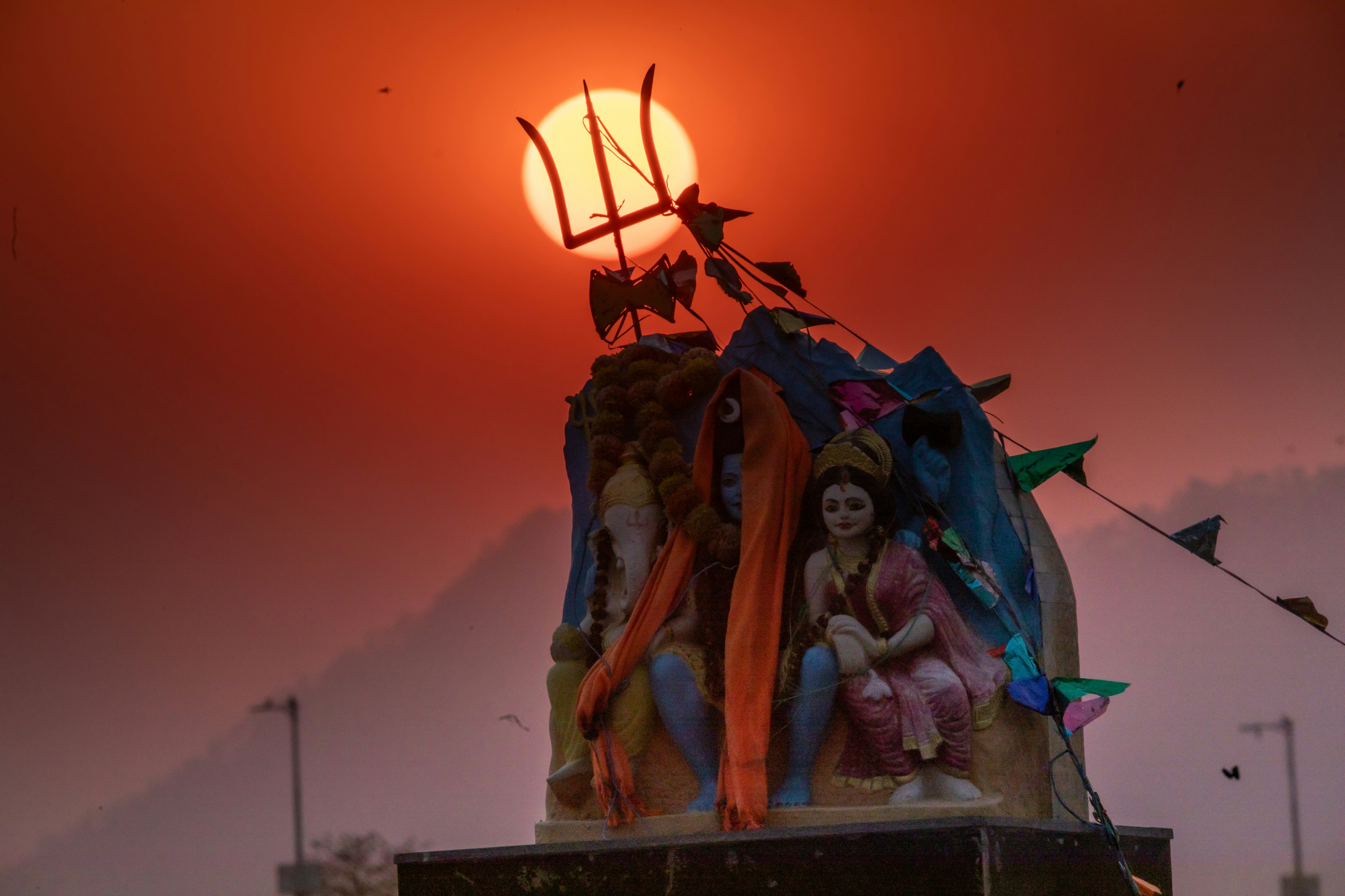 Statue of hindu deities against a fiery sunset