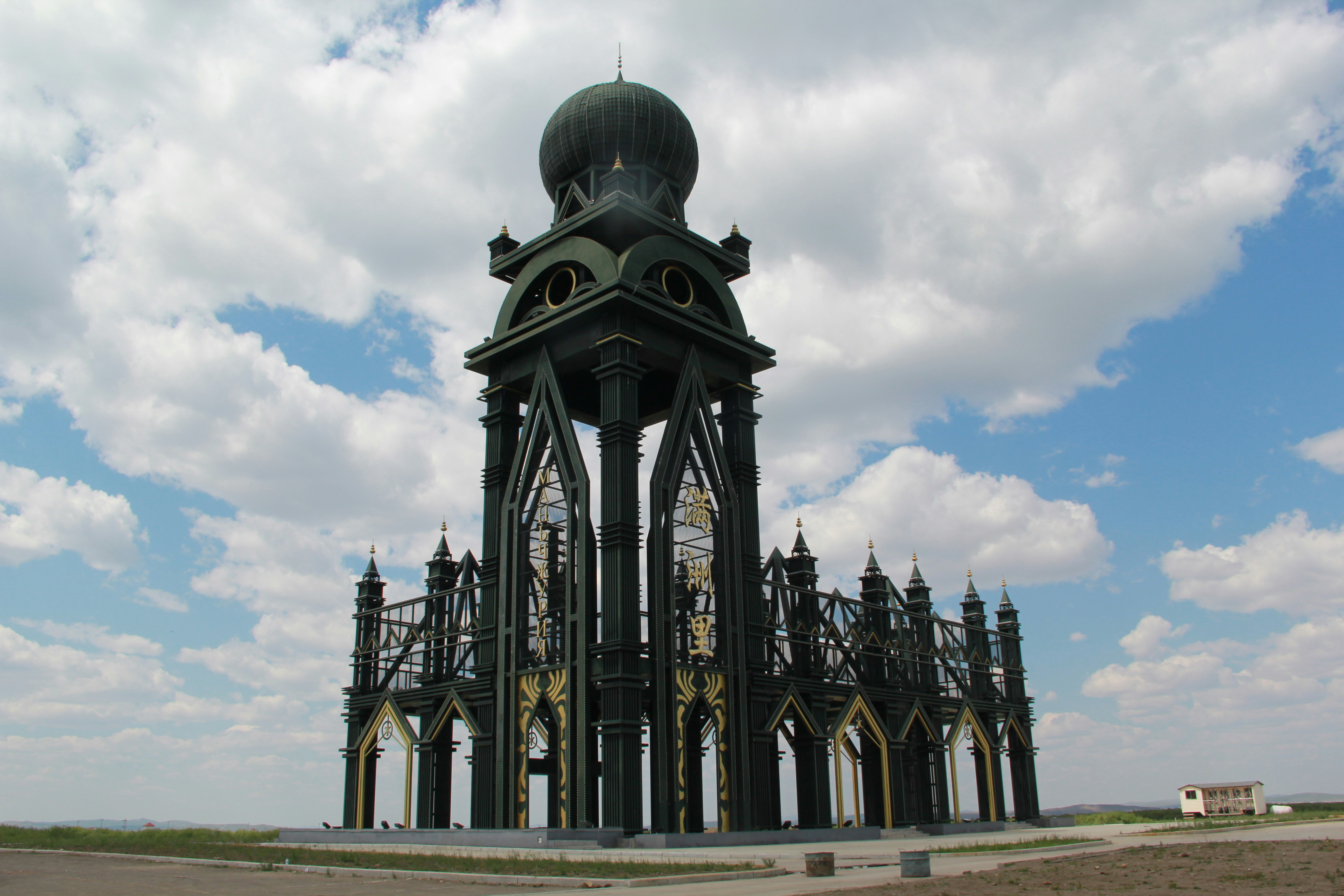 Ornate dark pavilion against a cloudy sky