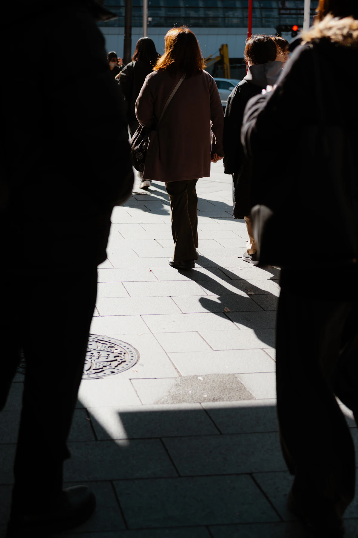Menschen gehen auf einem sonnigen Gehweg in der Stadt