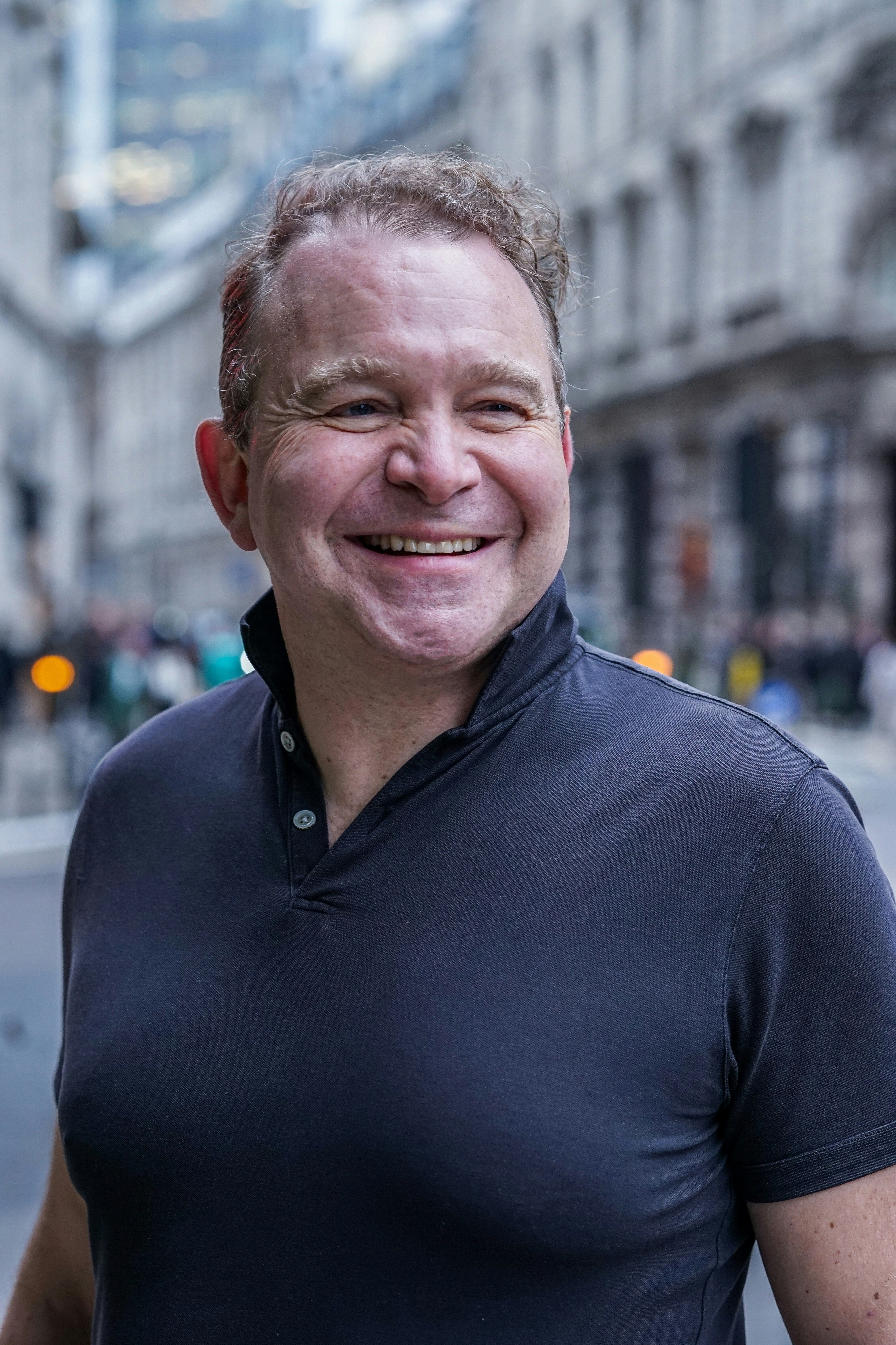 “Portrait of a smiling middle-aged man standing on a city street.”