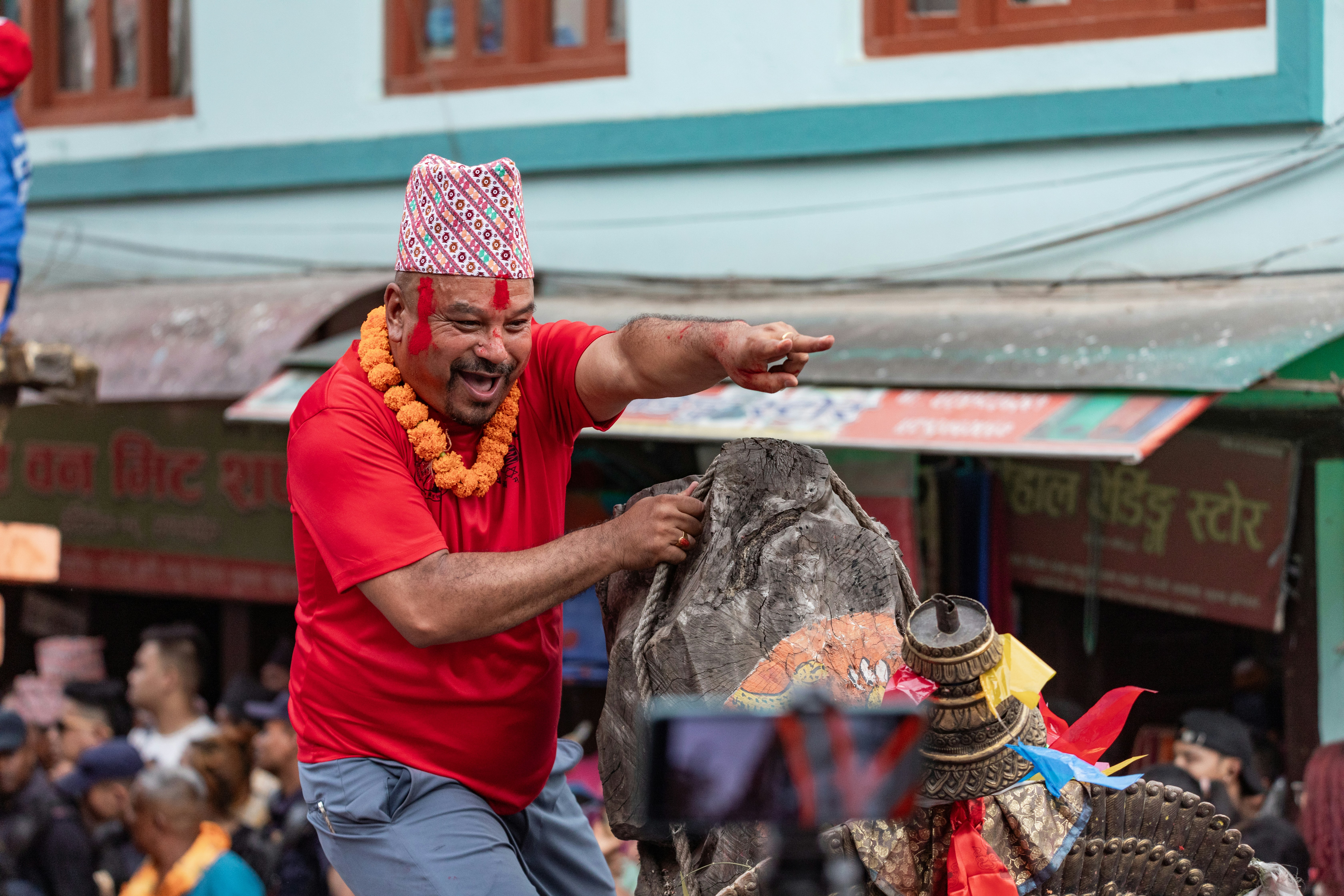 Man in red shirt and hat points during festival