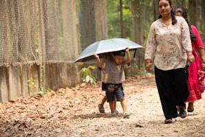 Children share umbrella while walking outdoors