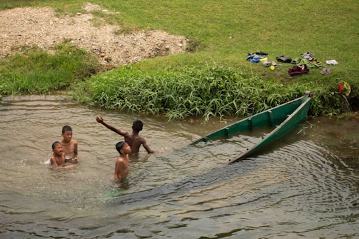 Children playing in a river near a boat