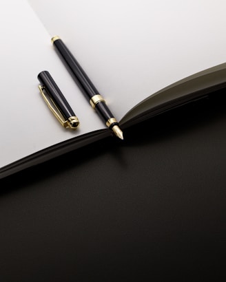 A black and gold pen rests on an open notebook.