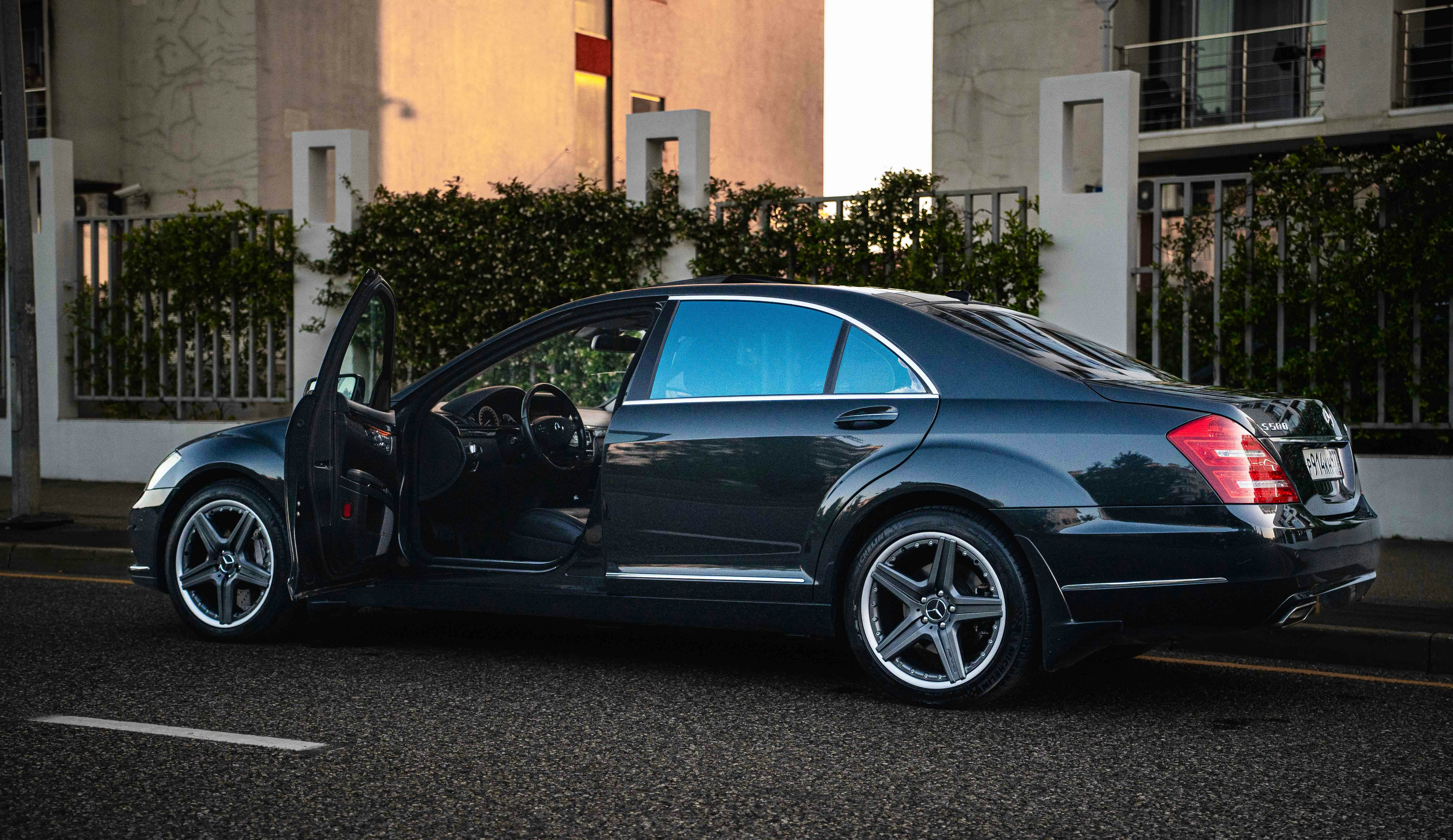 Luxury dark sedan with doors open on street