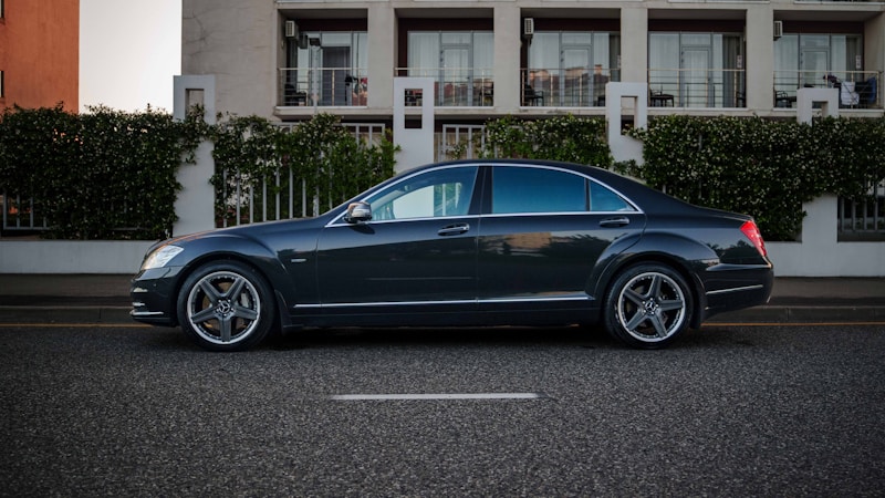 luxury dark sedan parked on upscale street