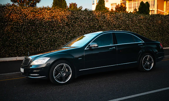 A dark luxury sedan parked on a street.