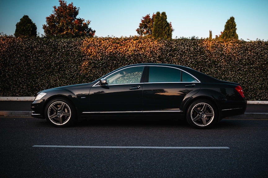 A black luxury sedan parked on the roadside.