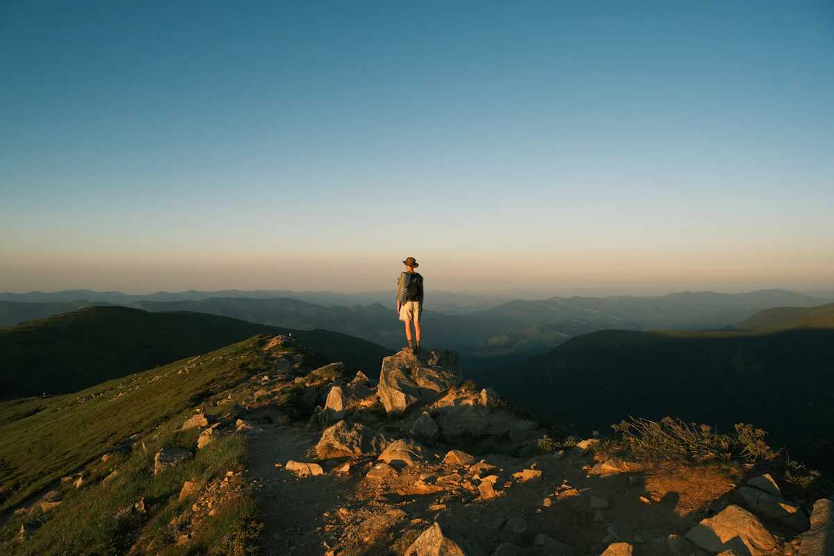 A person standing on a rocky lookout above a green valley