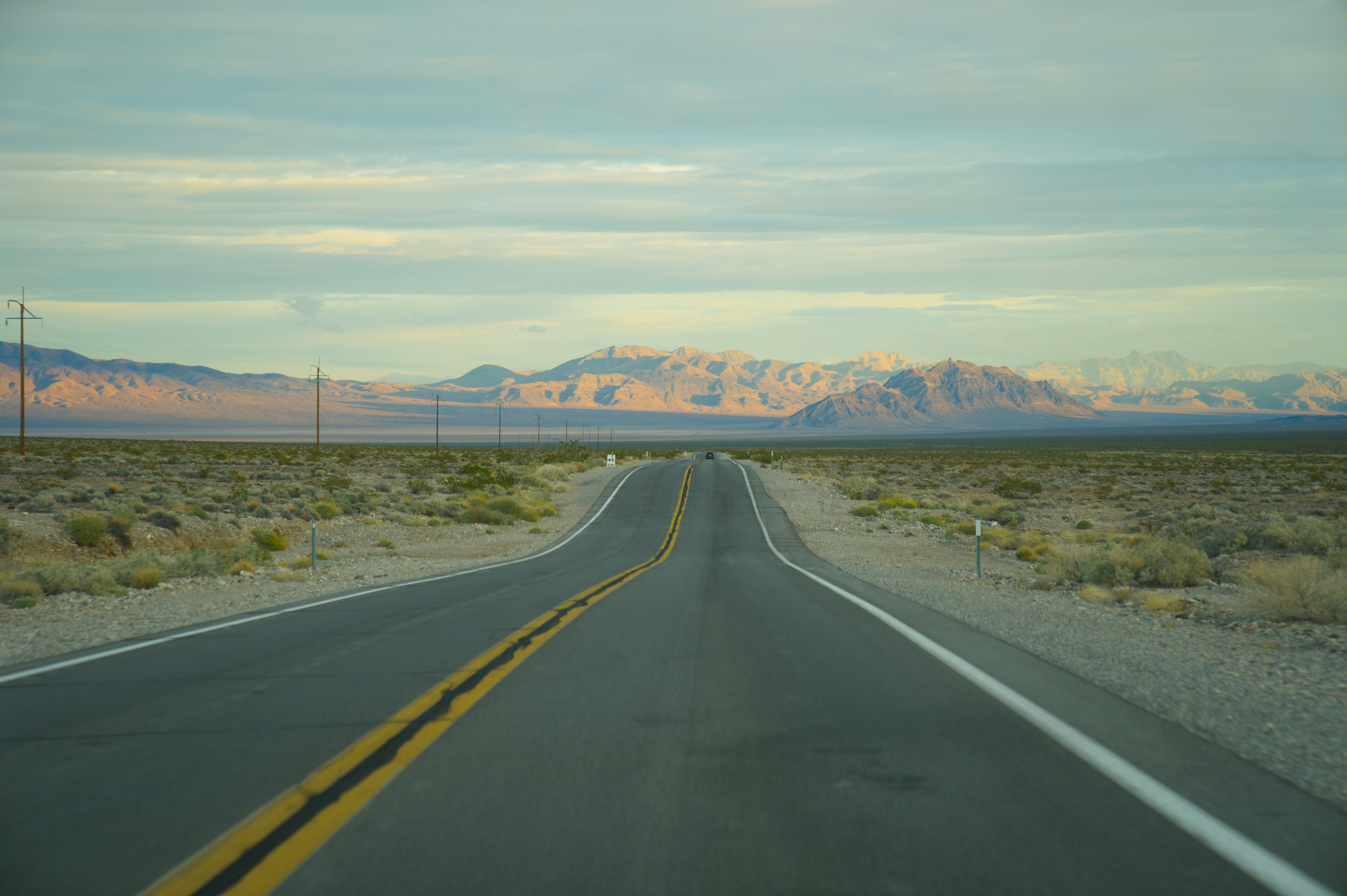 Empty desert highway leading to distant mountains.