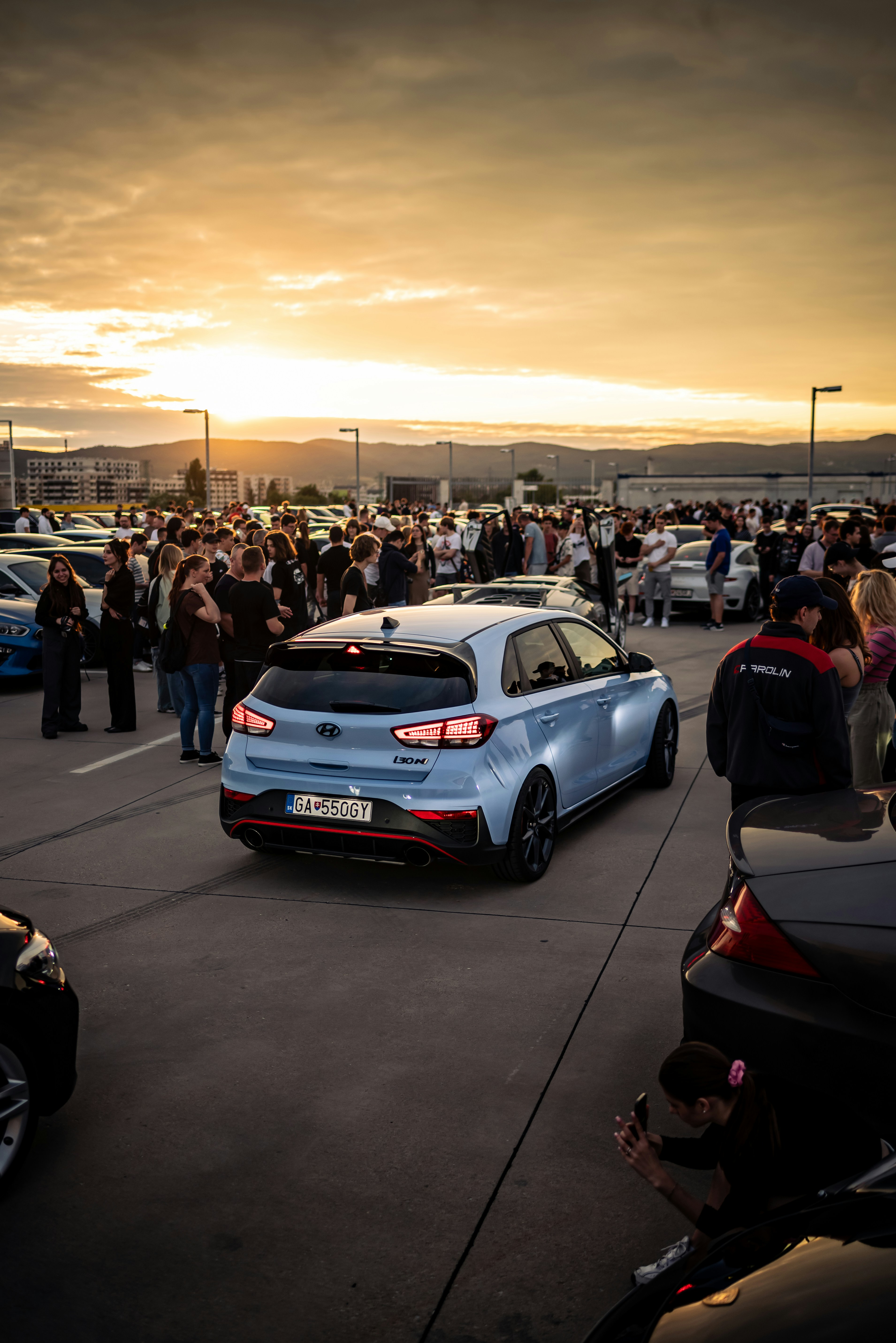 Cars and crowd at a car meet during sunset