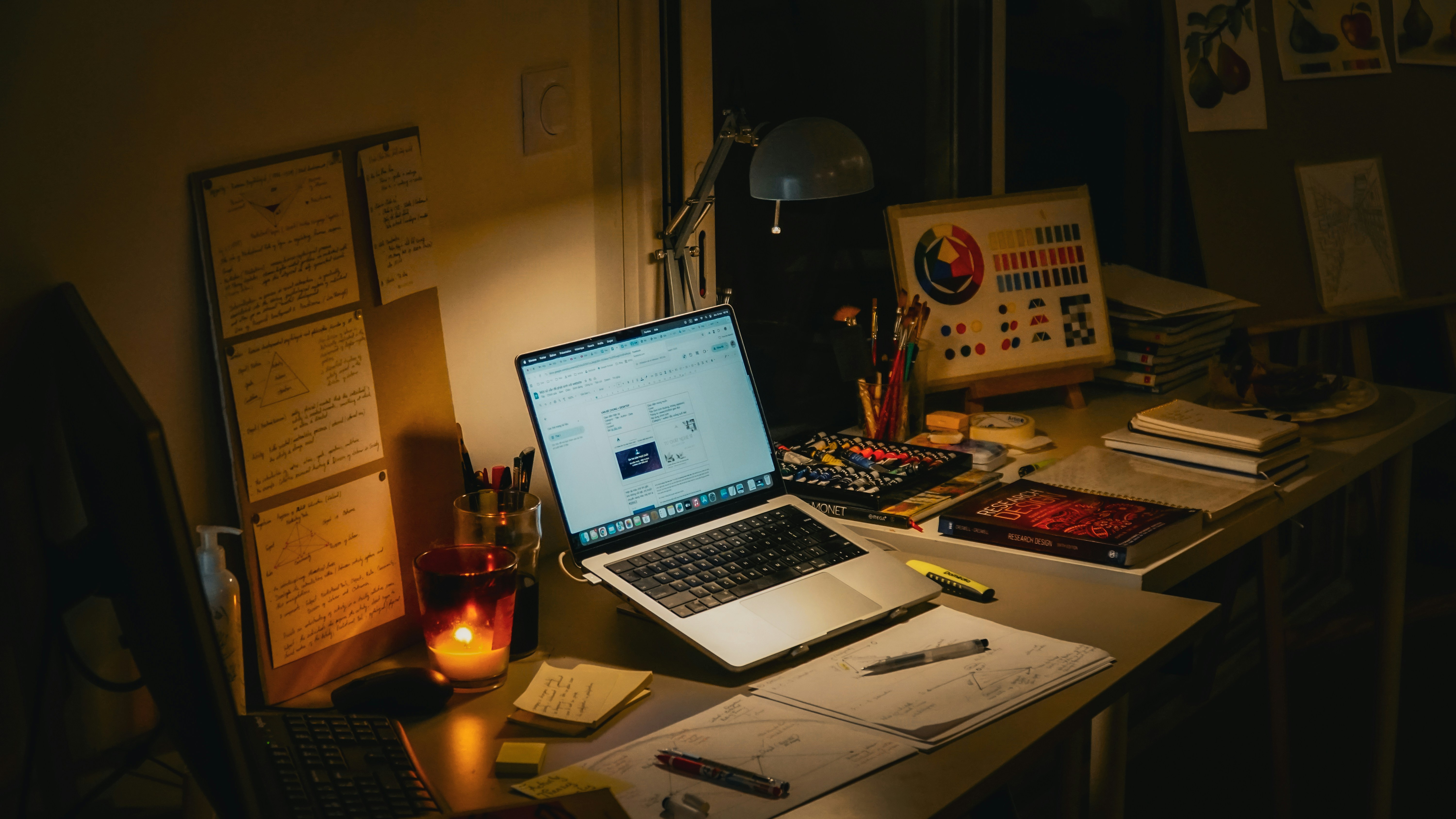 Desk with laptop, books, and lit candle