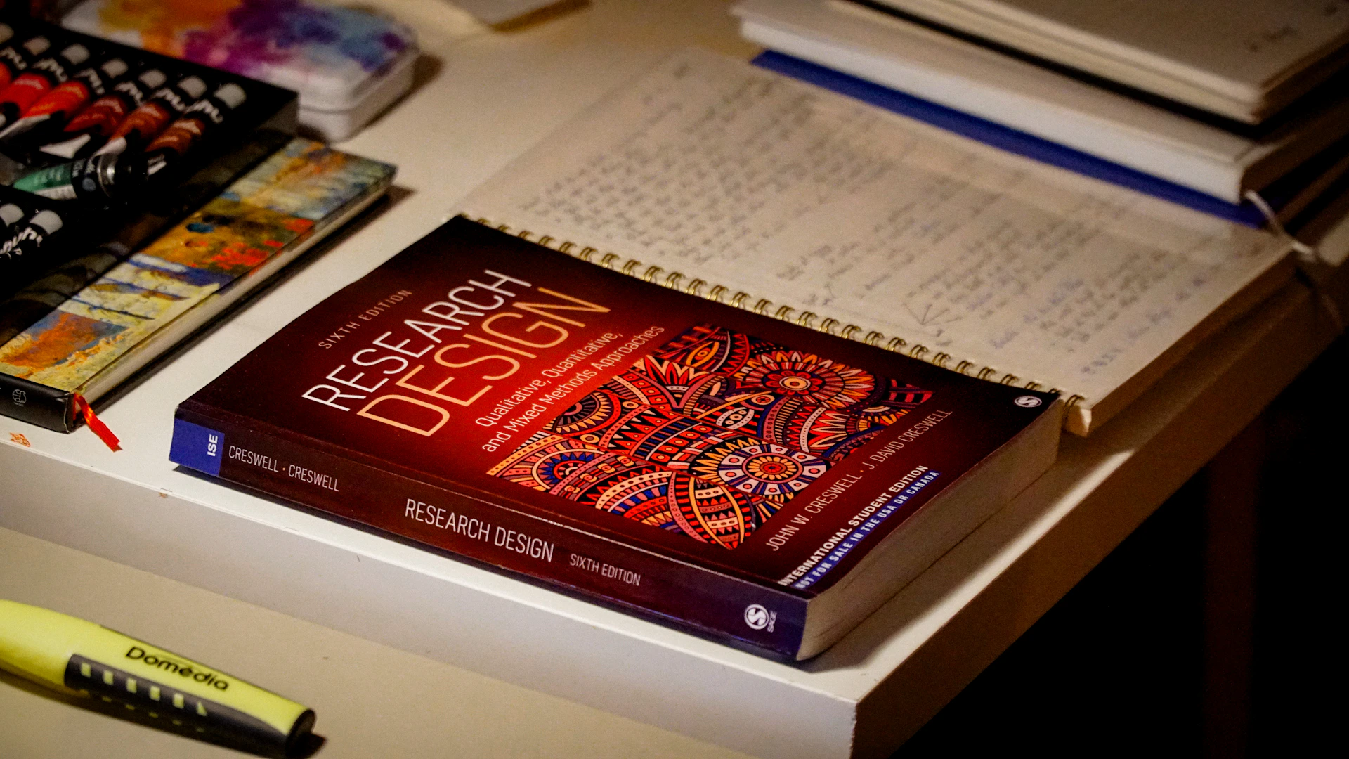 Research design book on a desk with notebooks.