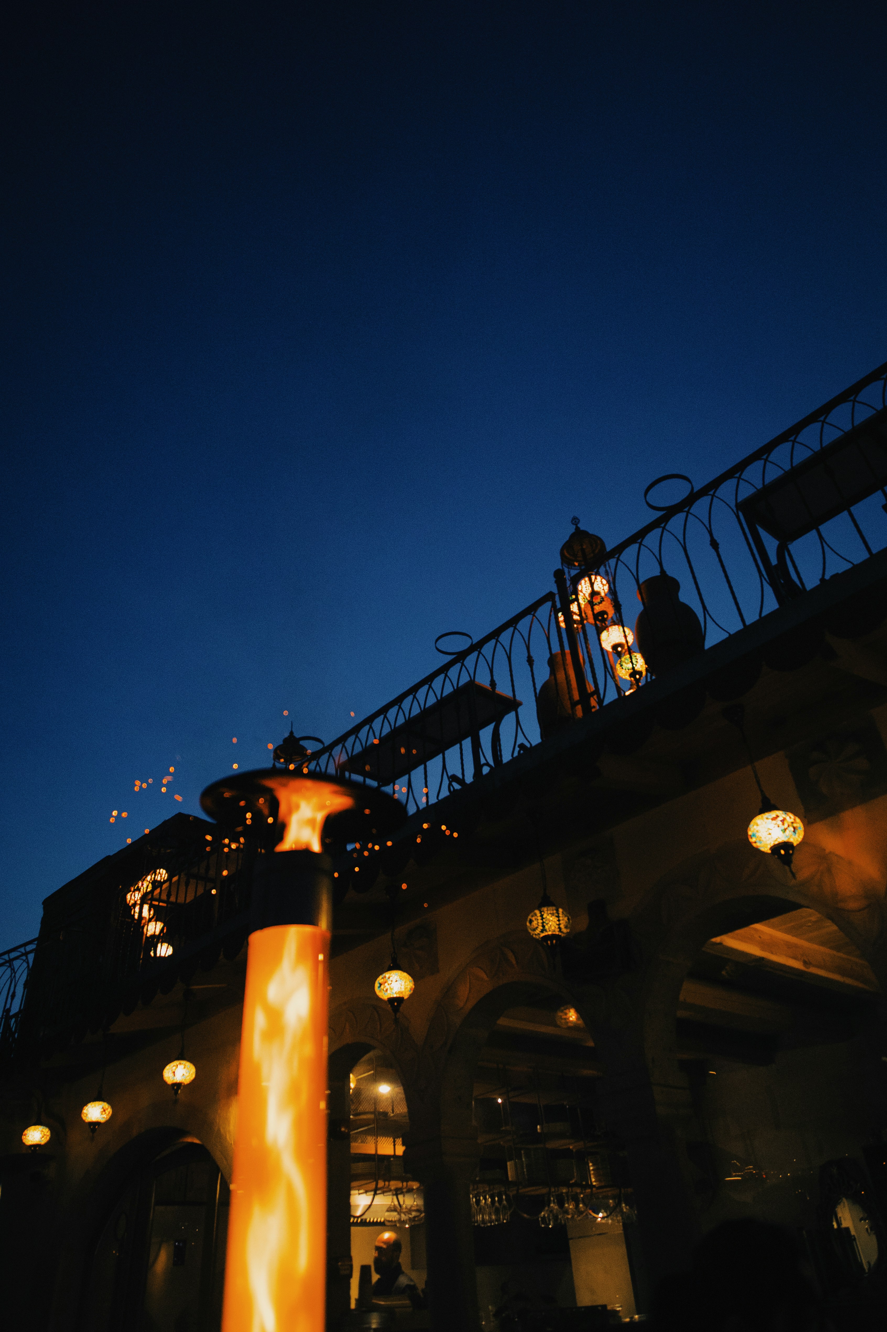 Outdoor patio with glowing heater and lanterns at dusk