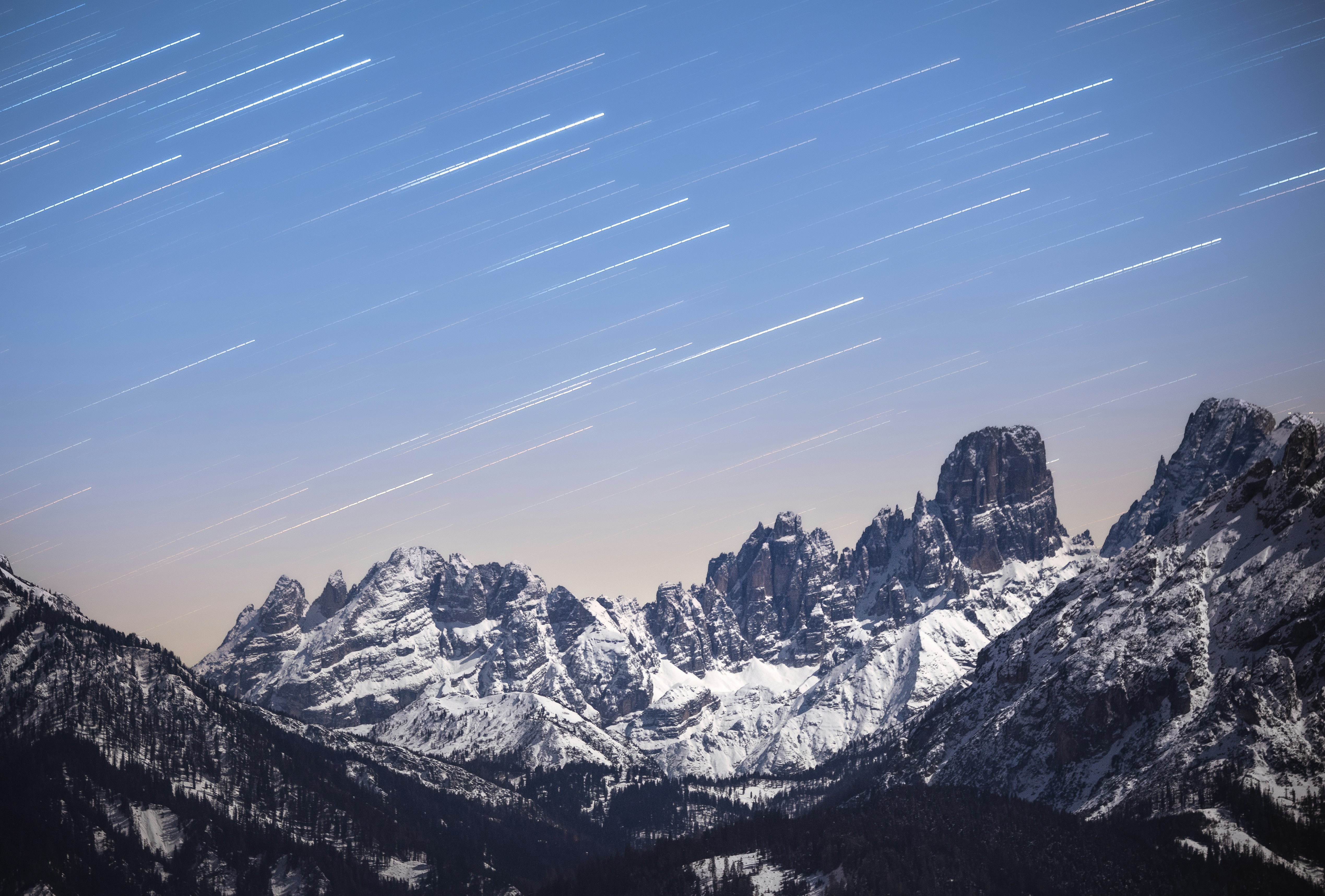 Star trails over snow-capped mountains at night