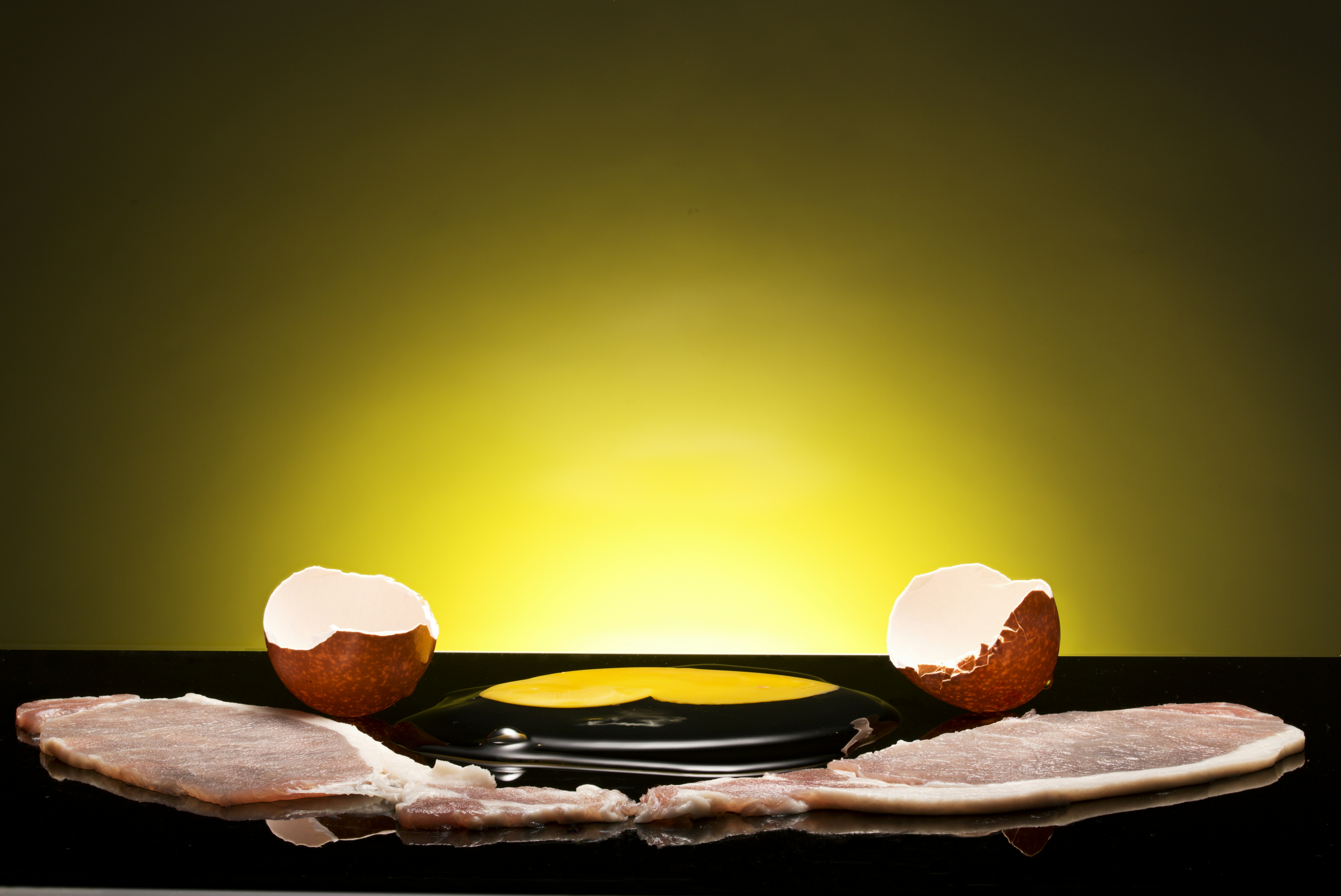 Two strips of bacon with cracked eggshell halves