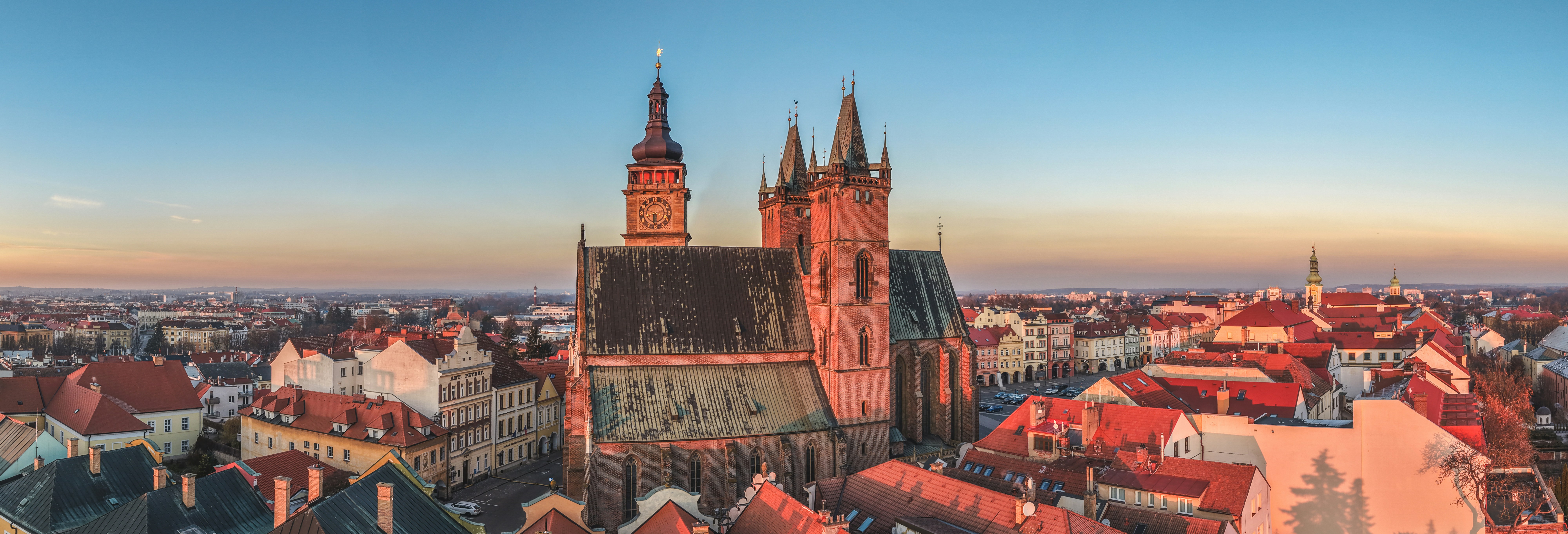 Historic church towers over red-roofed buildings at sunset.