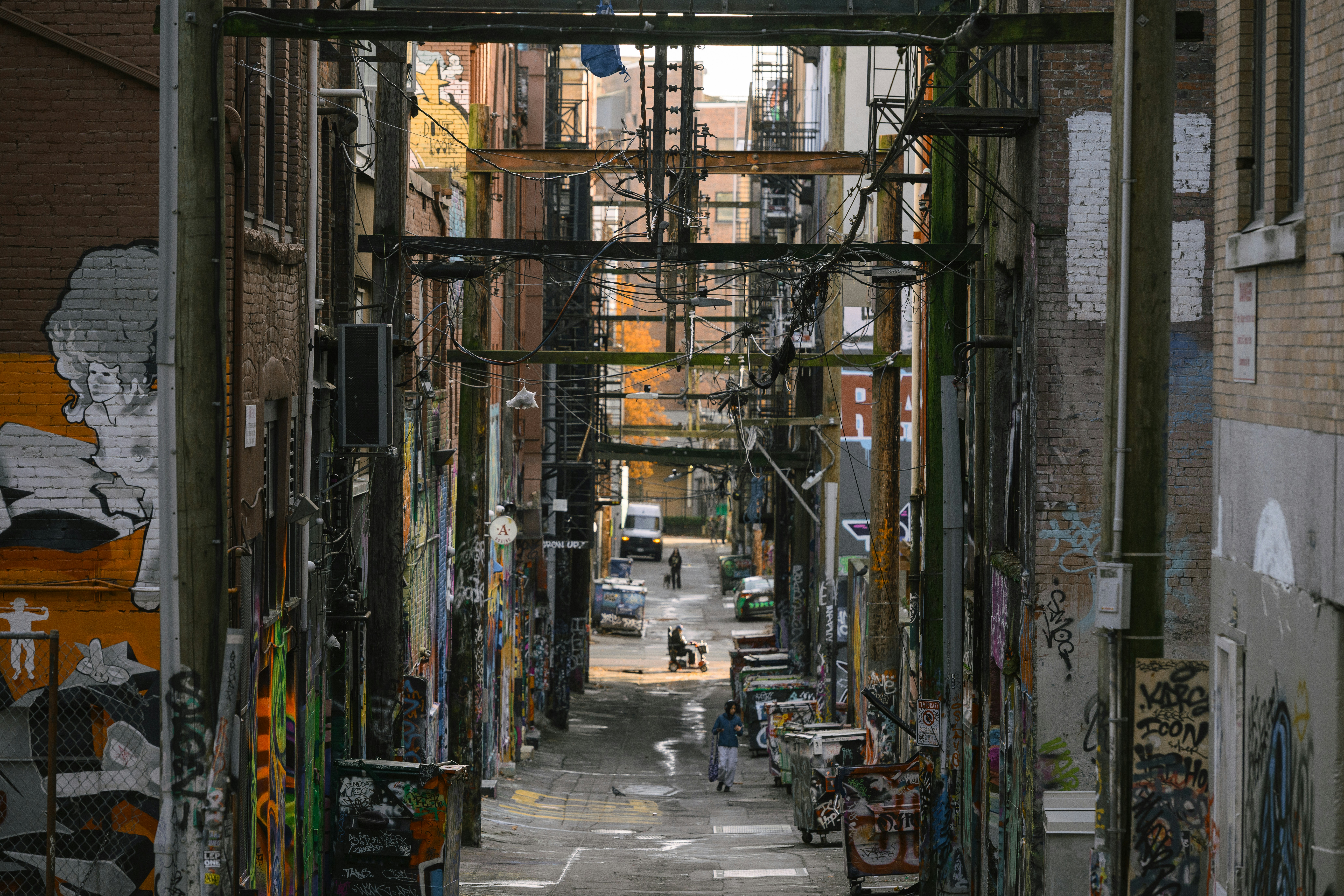 落書きだらけの路地で人々が歩いている