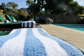 Blue and white striped towel on lounge chair by pool.