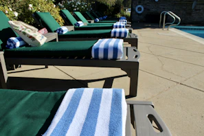 Green lounge chairs with blue striped towels by pool
