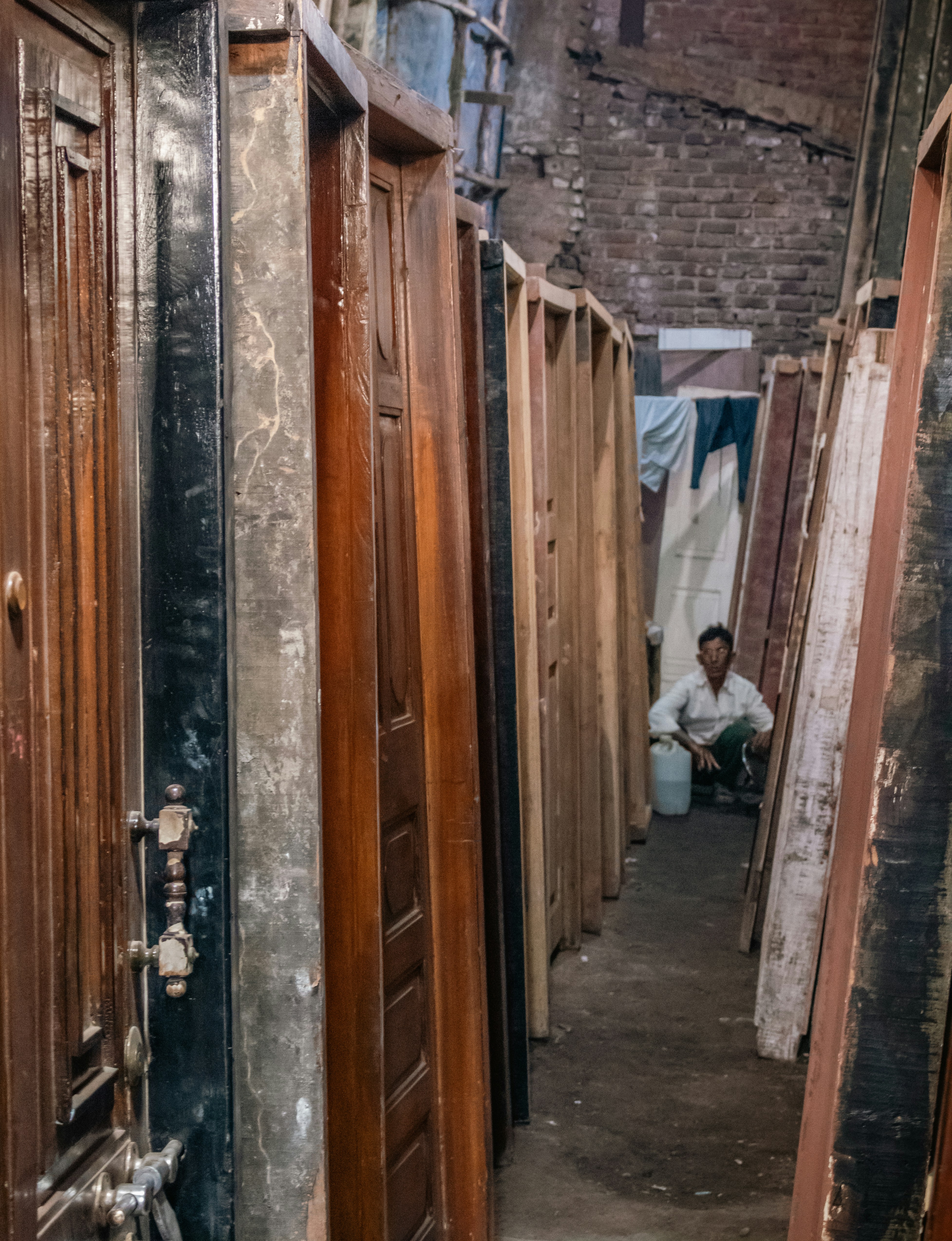 Man sitting among many wooden doors