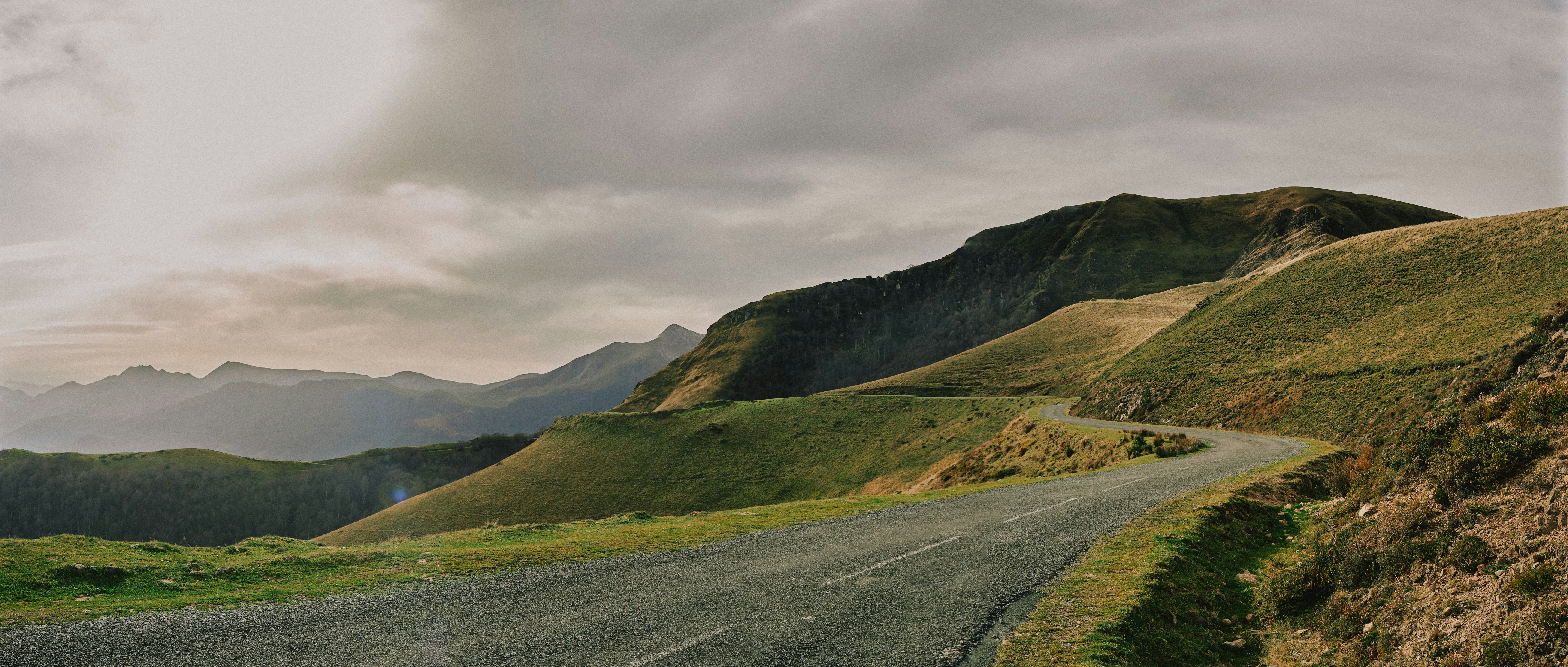 Winding mountain road under a cloudy sky