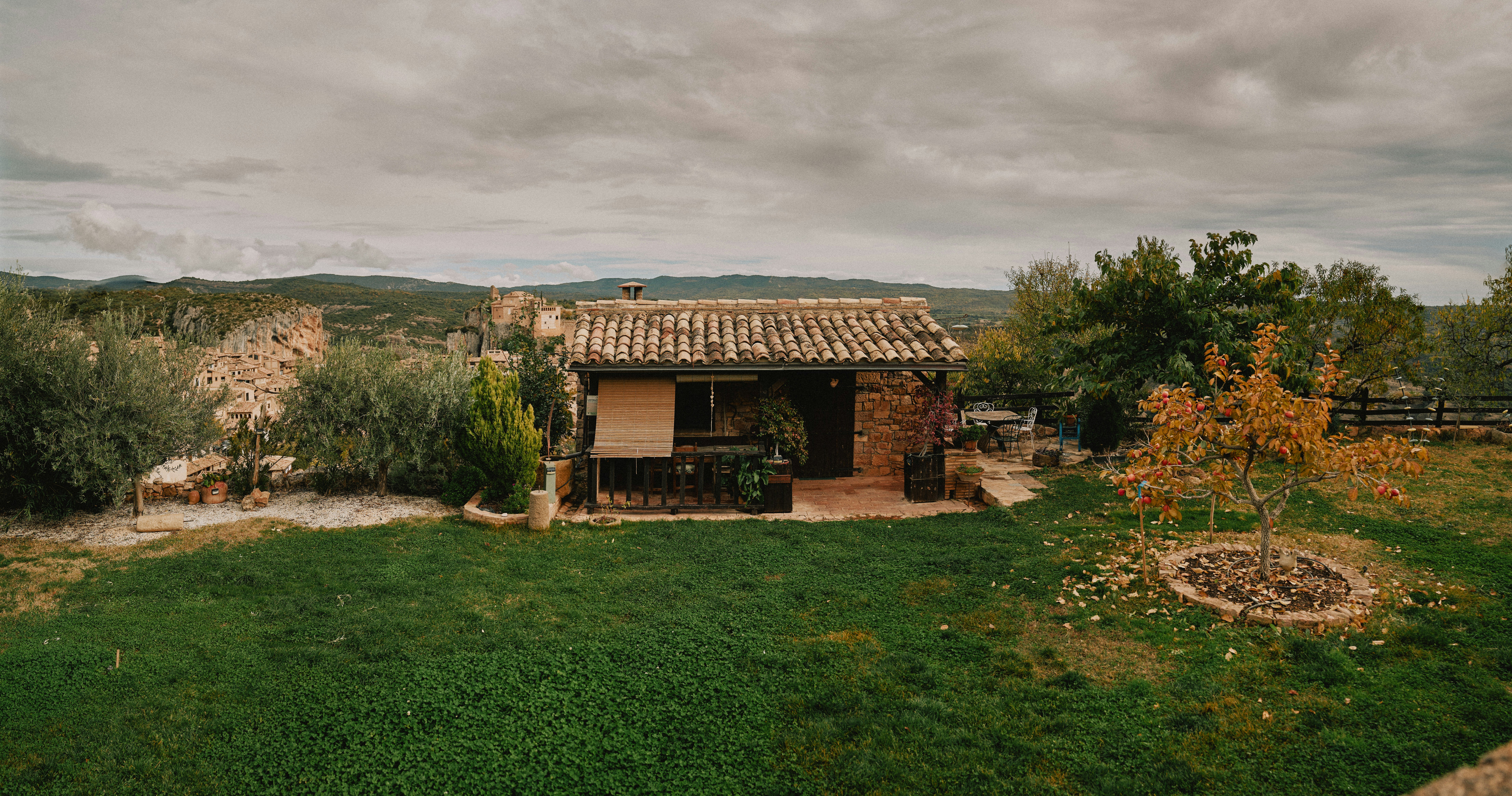 Small rustic cabin surrounded by trees and hills.