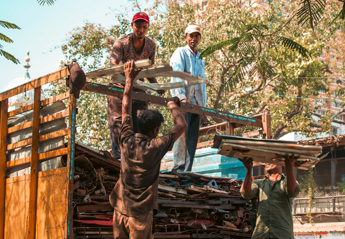 Workers loading scrap metal sheets onto a transport truck