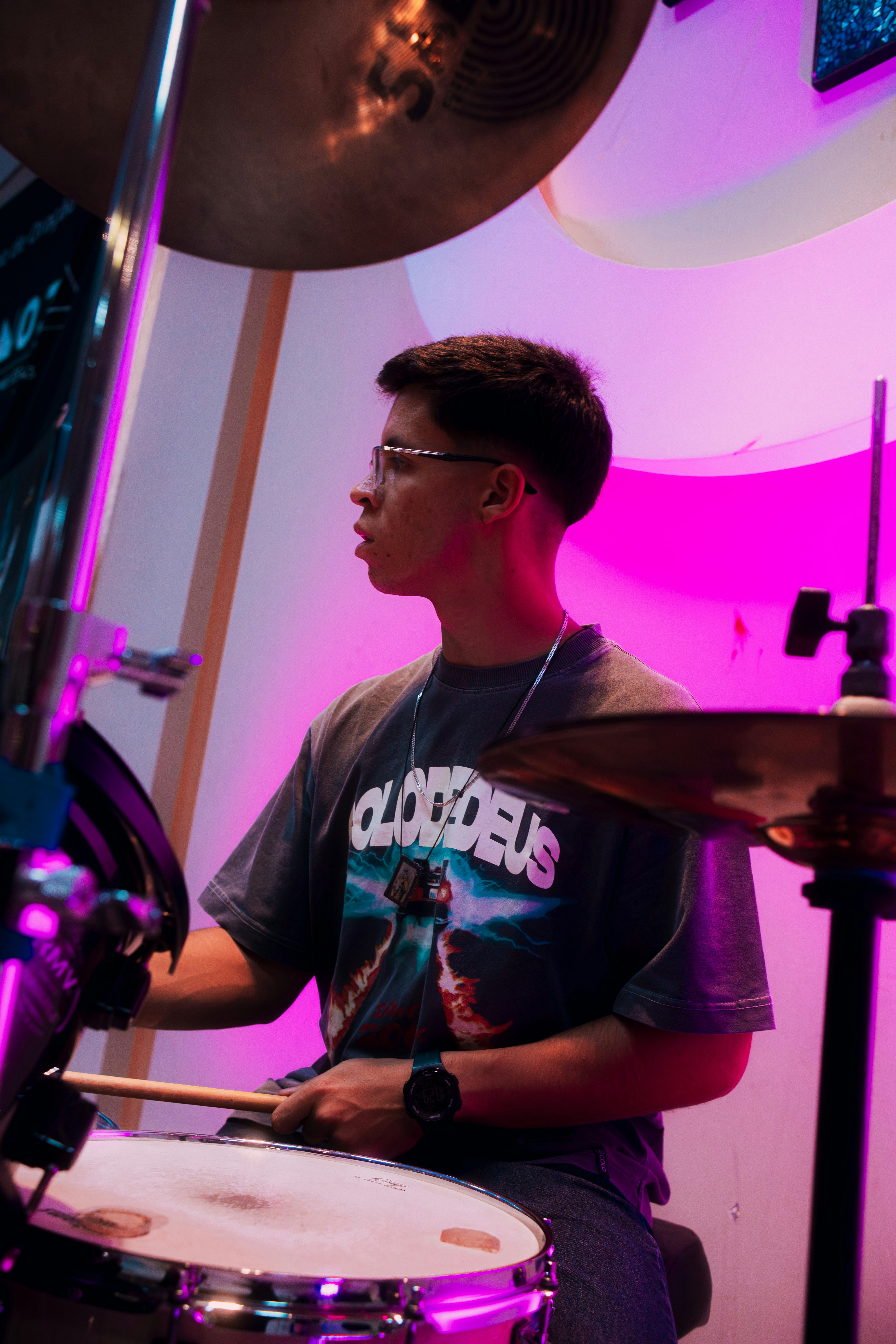 Young man playing drums with purple lighting