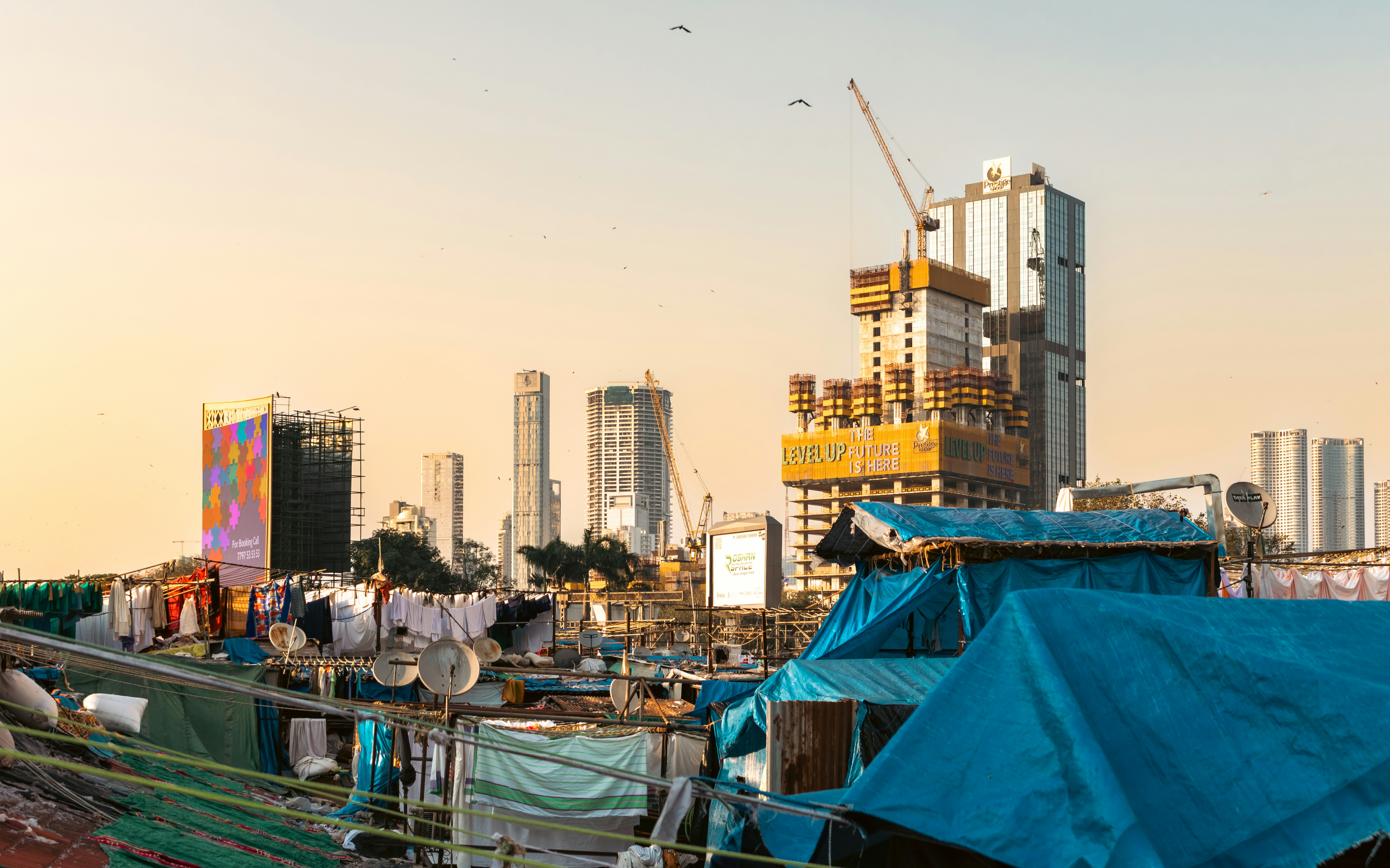Slum dwellings contrast with modern skyscrapers and construction.