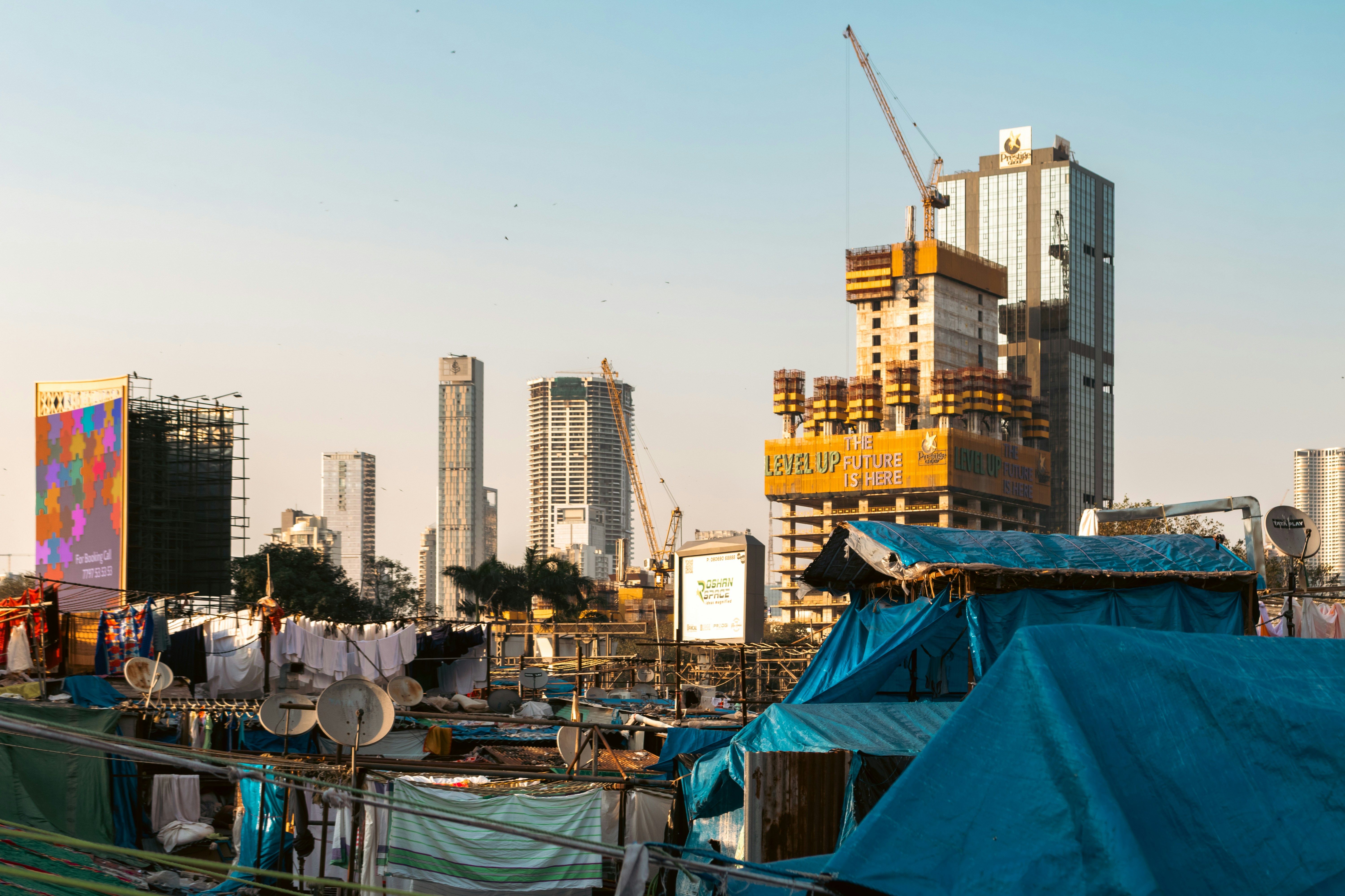 Skyscrapers under construction rise above makeshift homes.