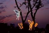 Glowing butterfly lights on a tree at dusk