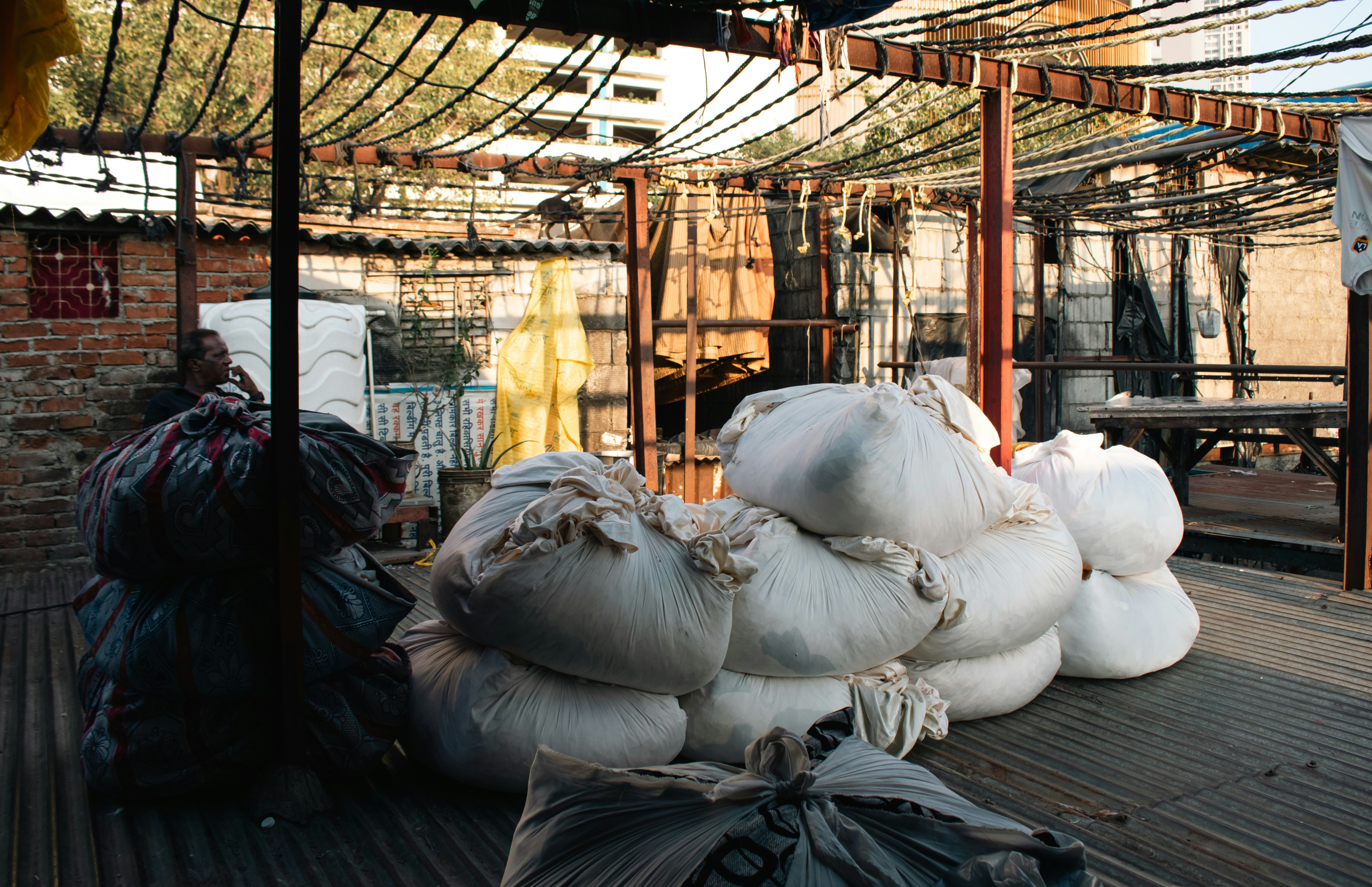 Large sacks of material piled outdoors under a canopy.