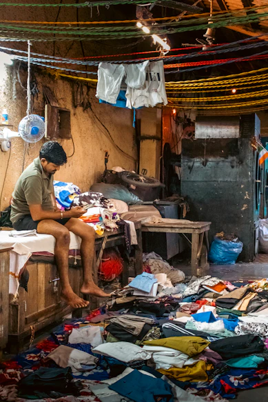 Man sitting amidst piles of clothes