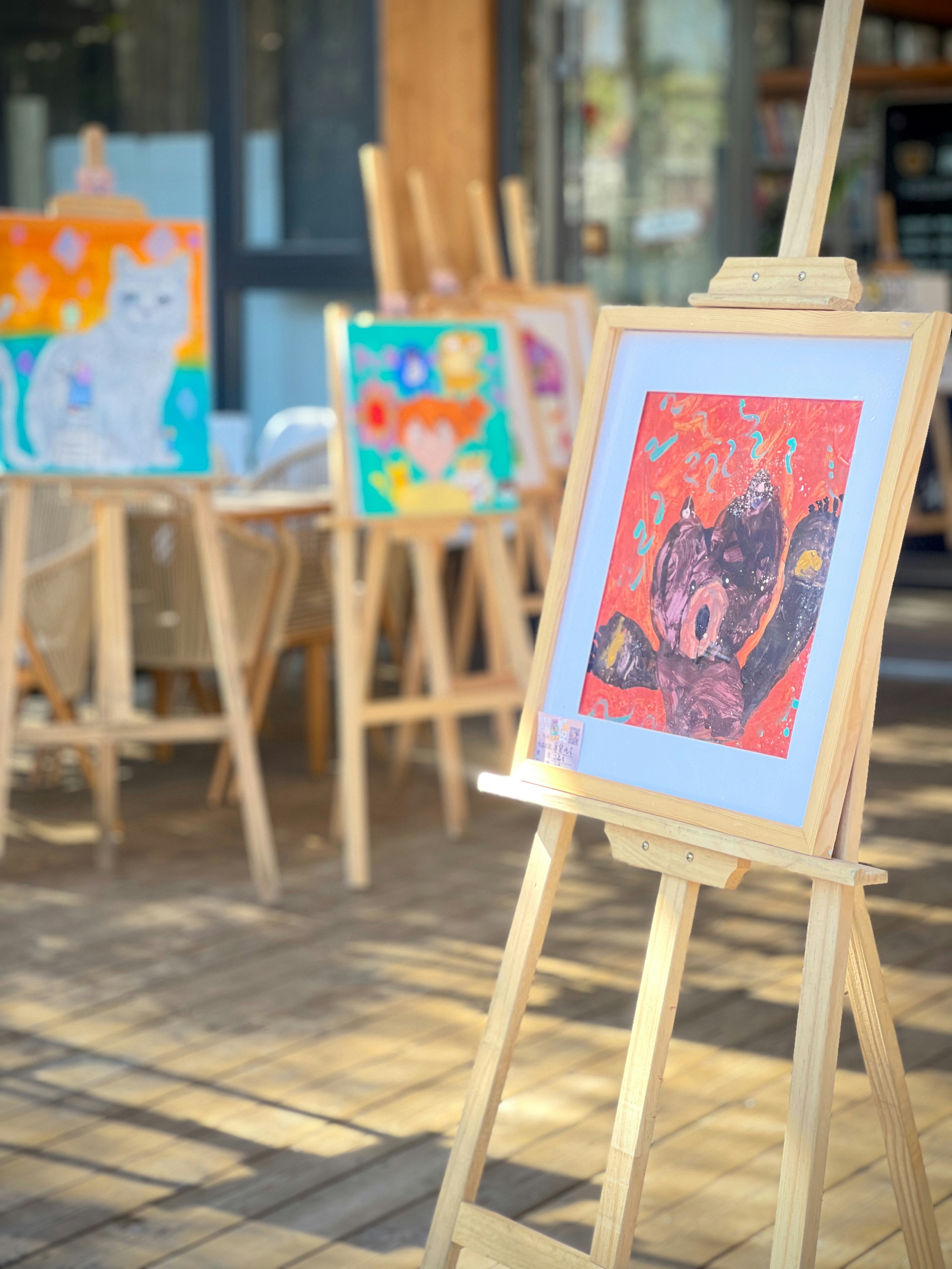 Children's colorful artwork displayed on easels outdoors.