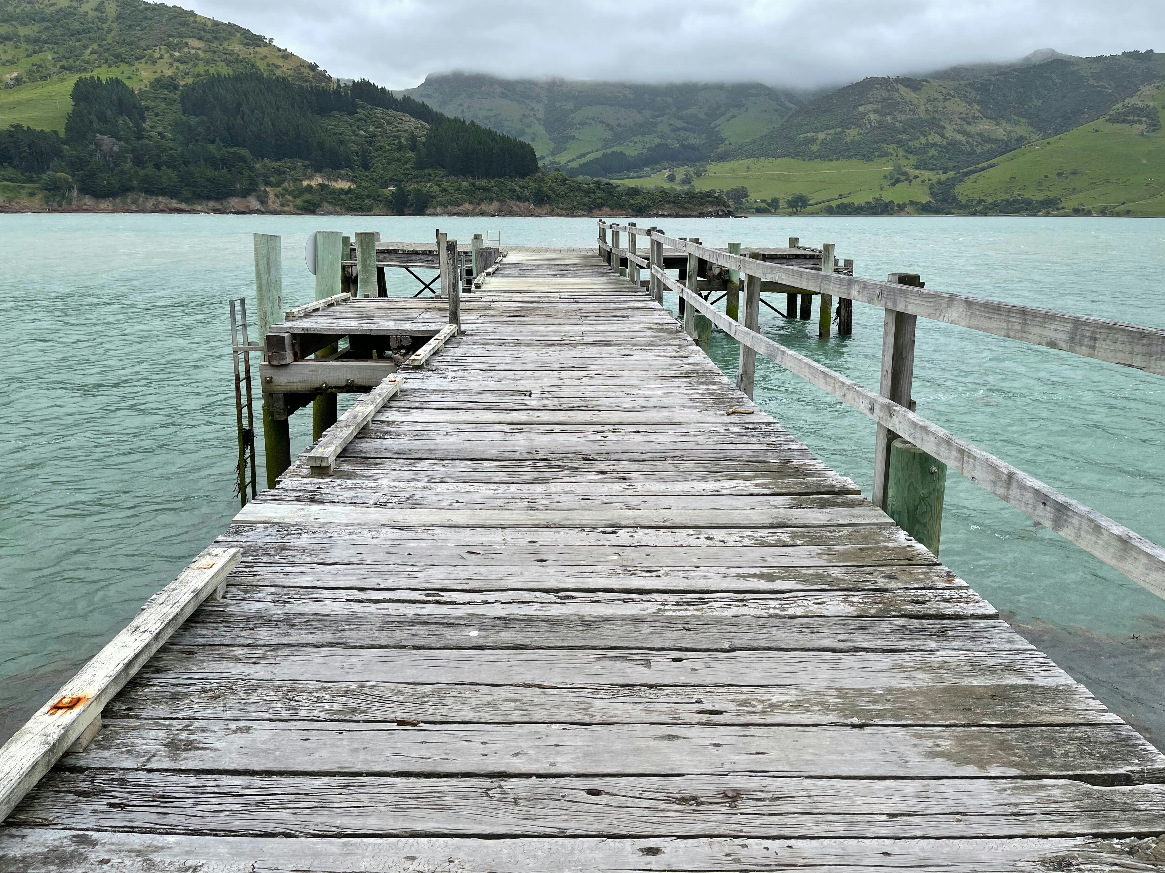 잔잔한 청록색 물속으로 뻗은 목조 부두가