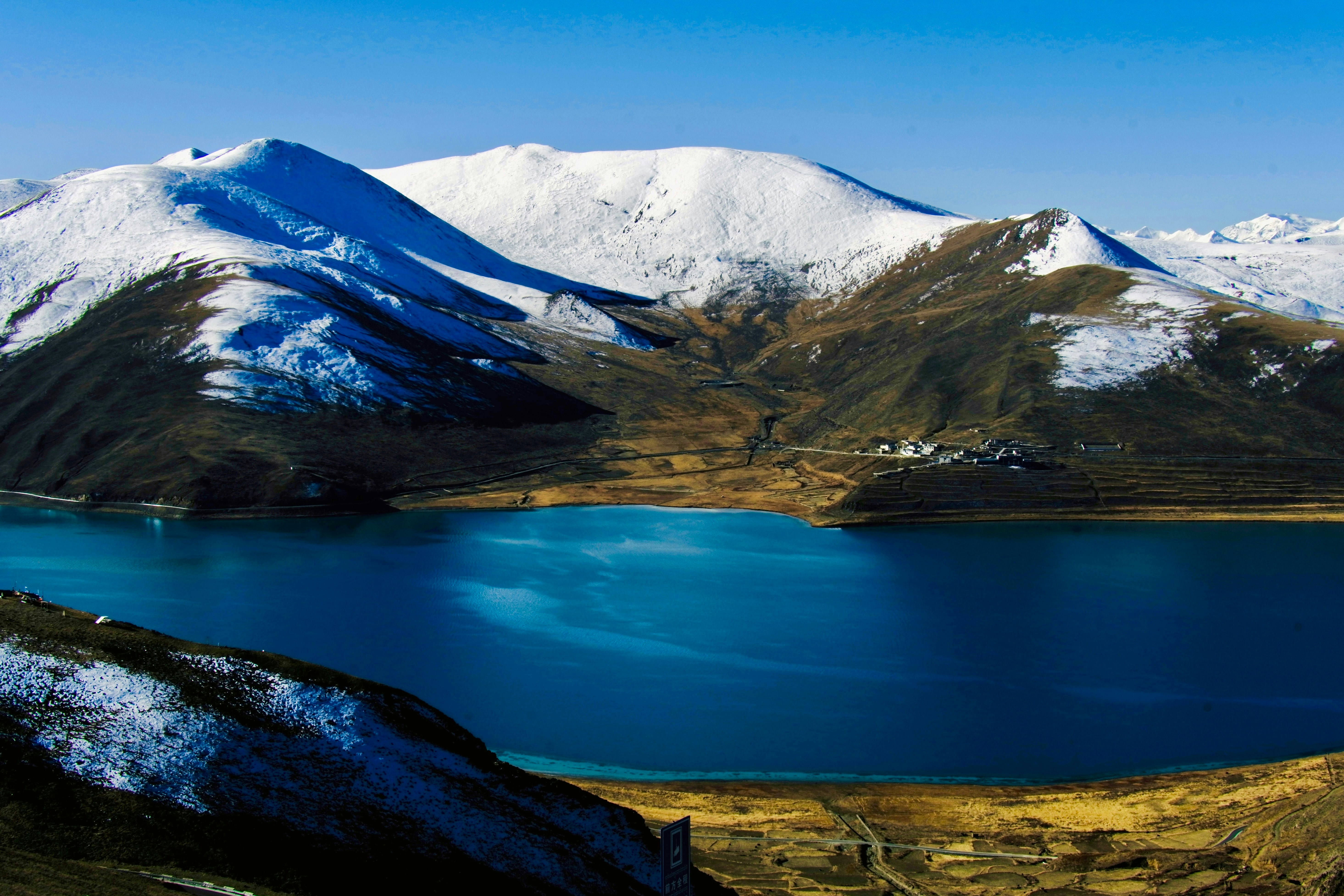 Snow-capped mountains reflected in a vibrant blue lake.