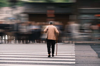 Elderly man with cane crossing busy street